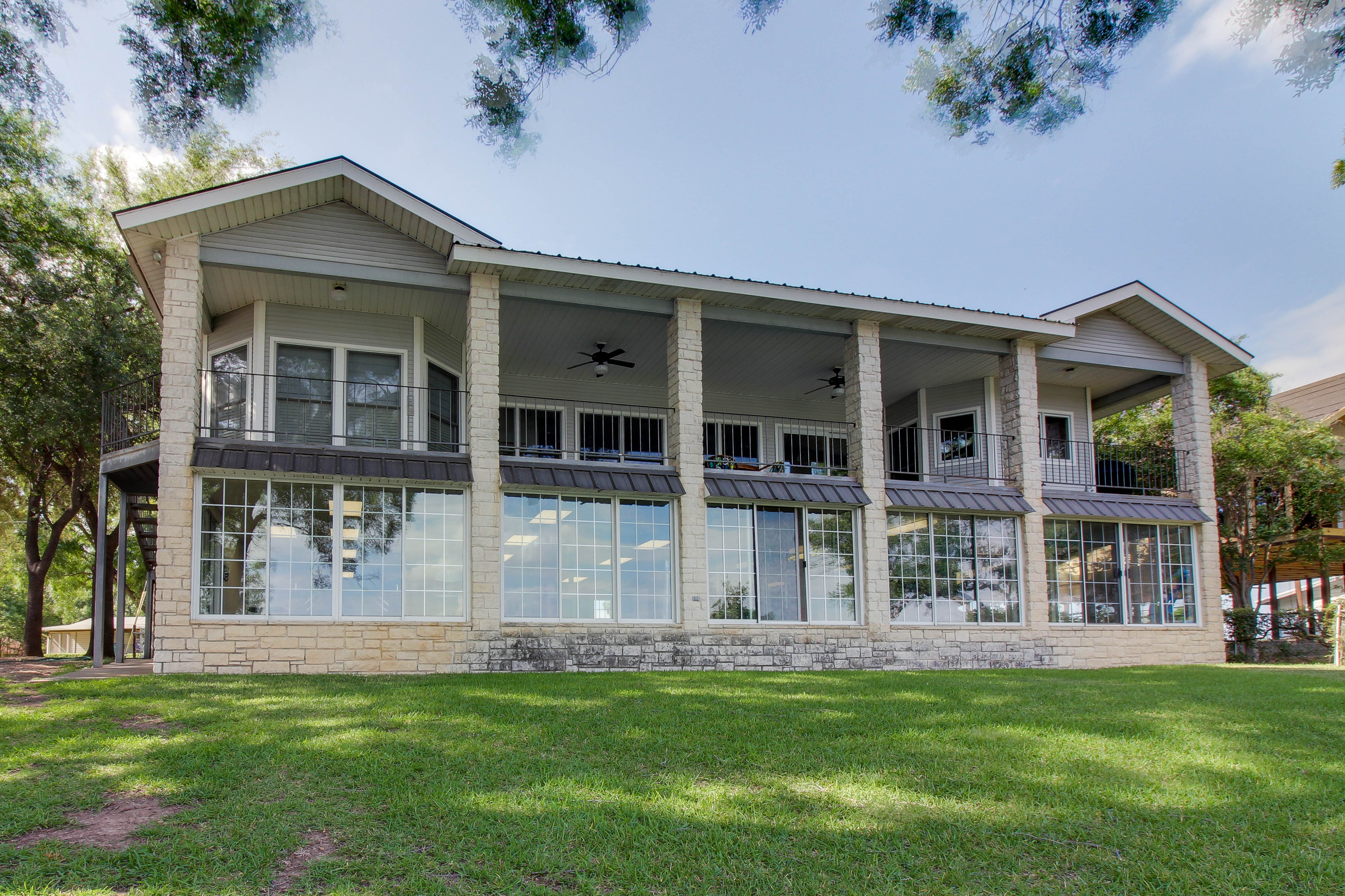 sprawling riverside home in Texas featuring a covered balcony and large grassy yard
