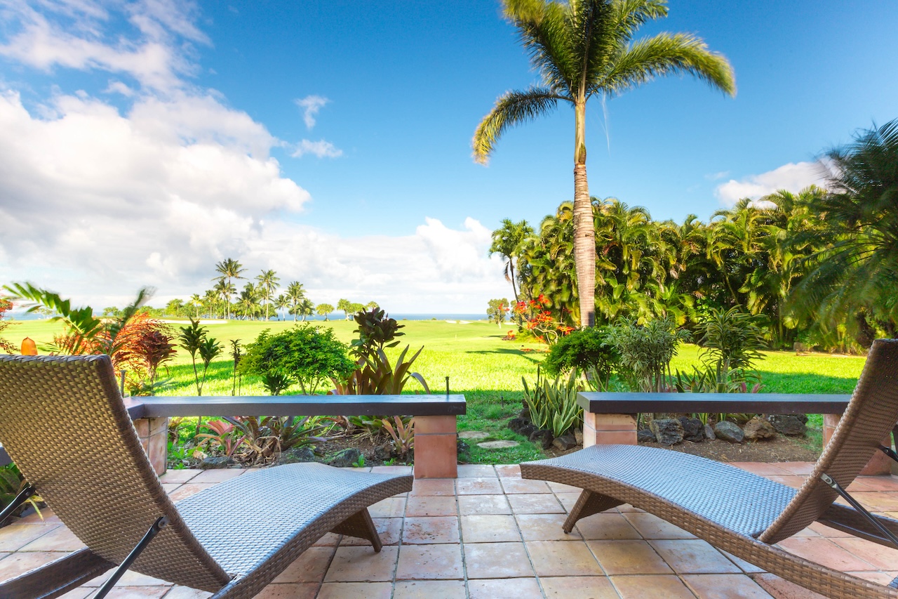 Two chairs overlooking a lush Hawaiian golf course.