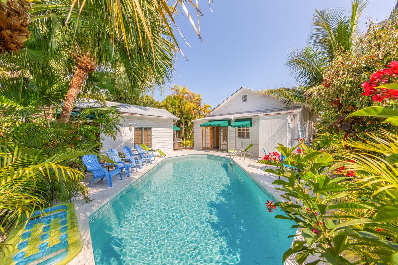 An outdoor pool with blue pool chairs at a vacation home rental in Key West, FL.