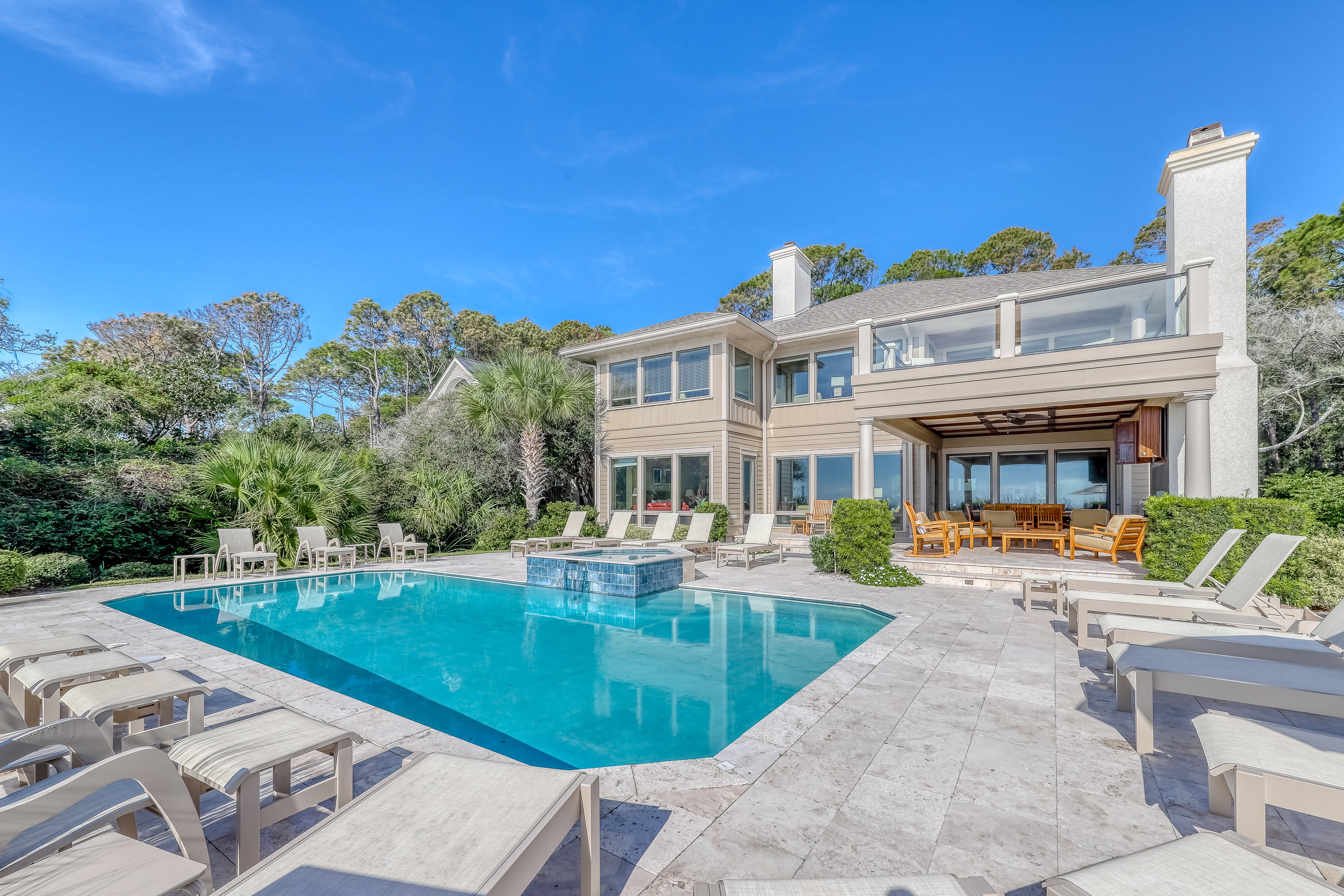 private pool with plenty of outdoor furniture with hilton head vacation home in the background