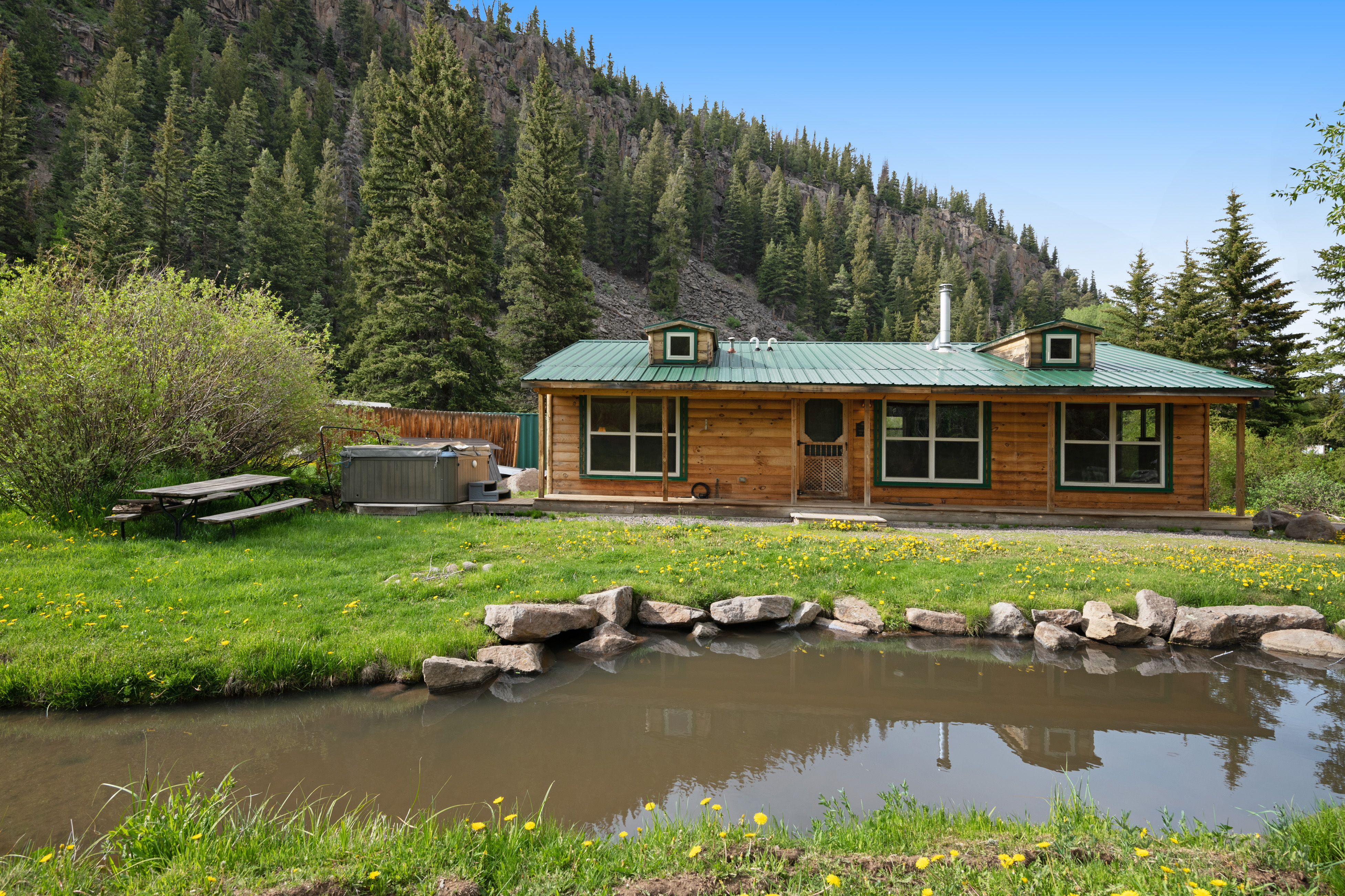 Cabin on the river with mountains in the background in Colorado.