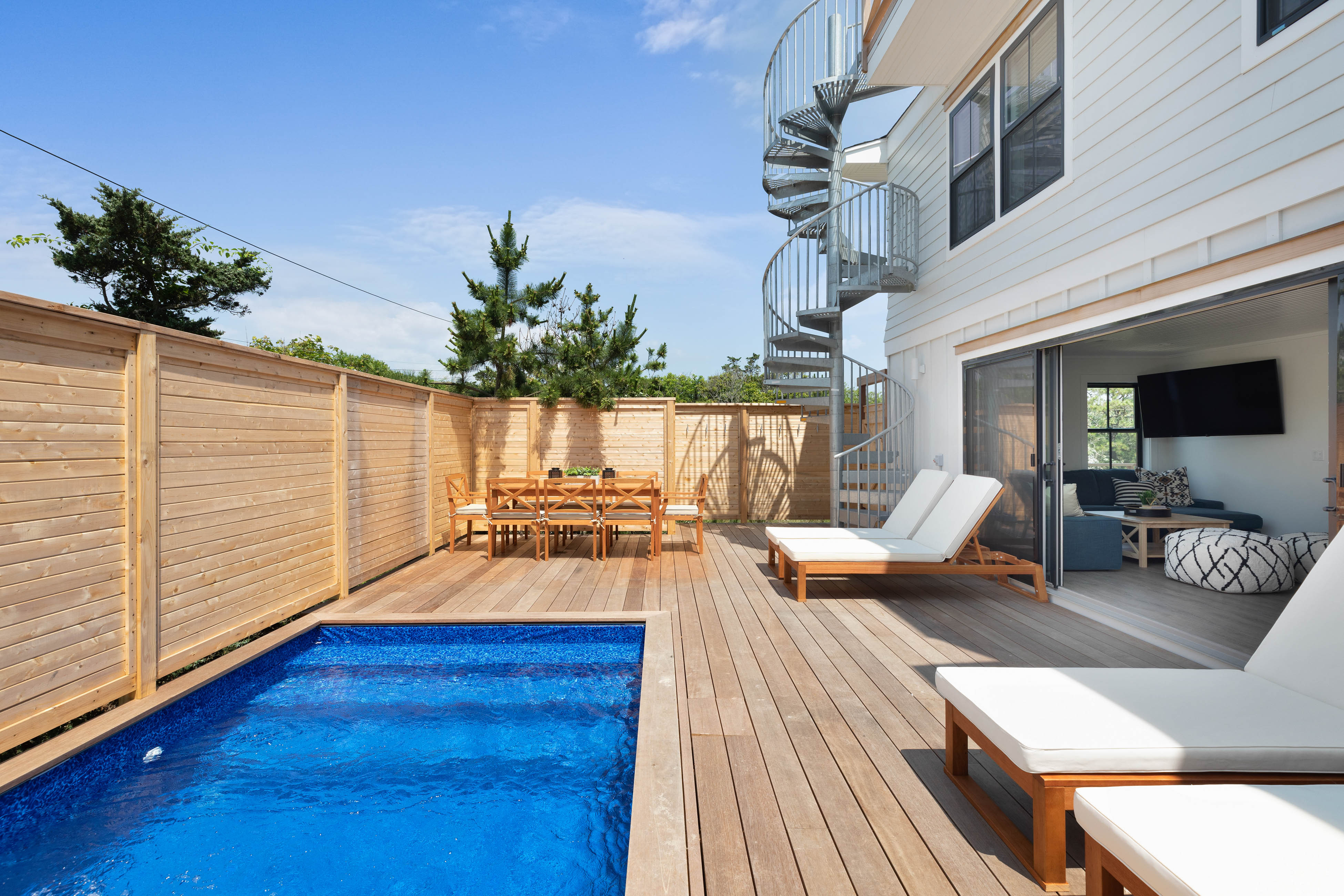 vacation rental with outdoor spiral staircase and pool surrounded by lounge chairs