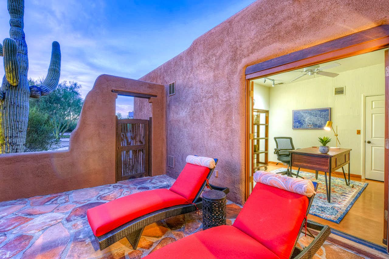 large cactus near vacation rental patio with red lounge chairs