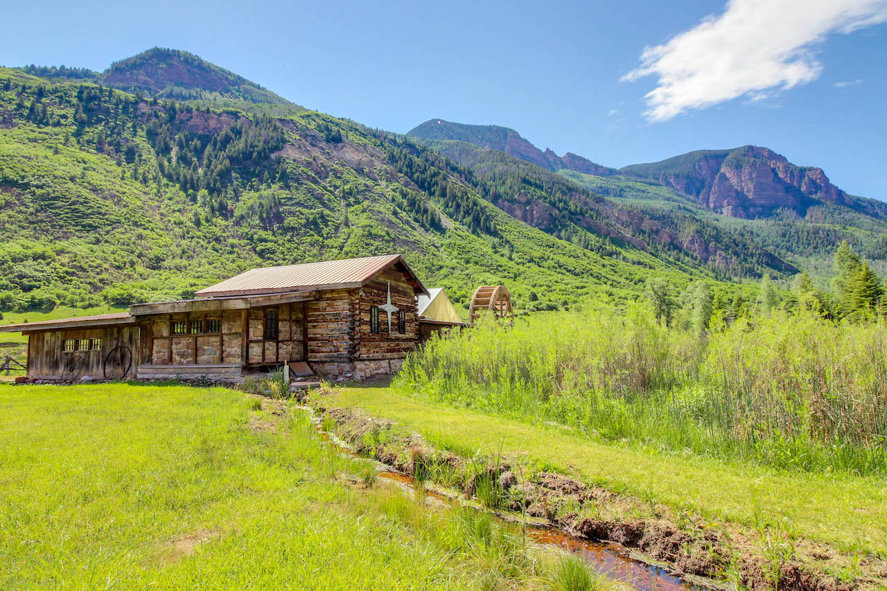 Cabin overlooking wildness and a river with mountains behind it in Redstone, CO.