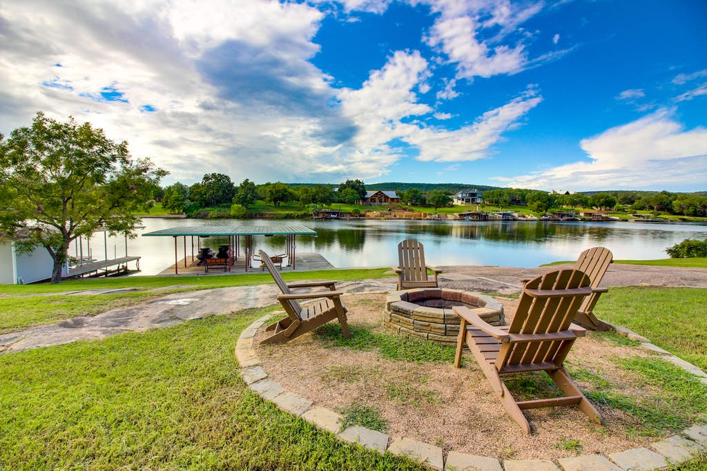 Firepit surrounded by adirondack chairs near a river in Texas