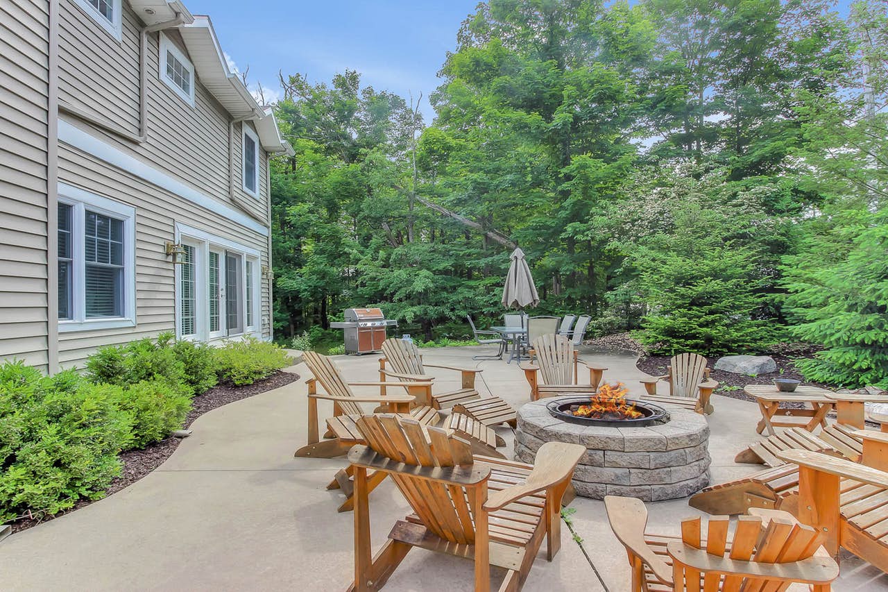 outdoor patio of vacation rental with firepit, gas grill, and ample seating
