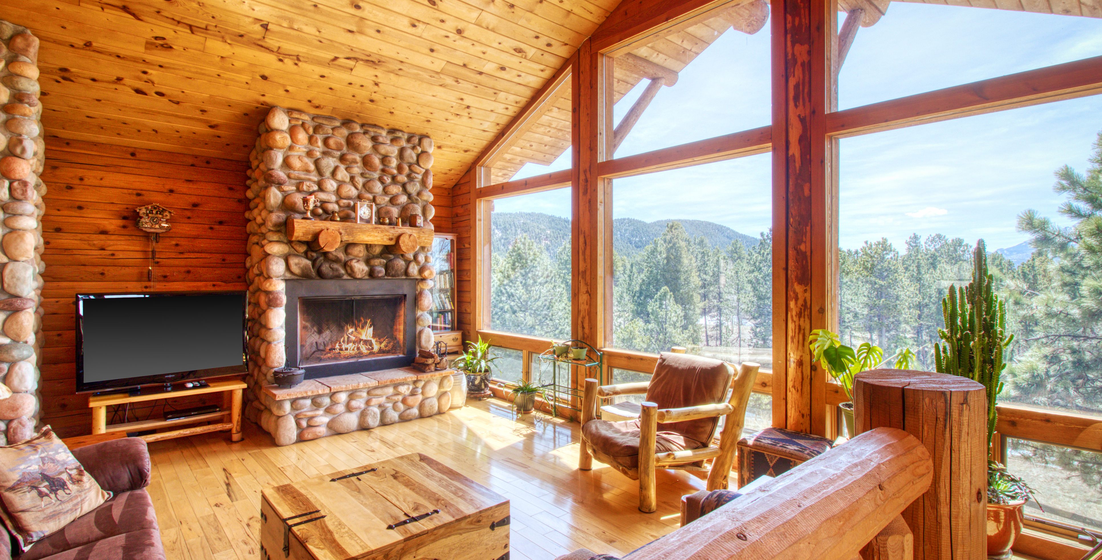 gorgeous wood accented interior of cabin with large fireplace and huge windows in woodland park, co