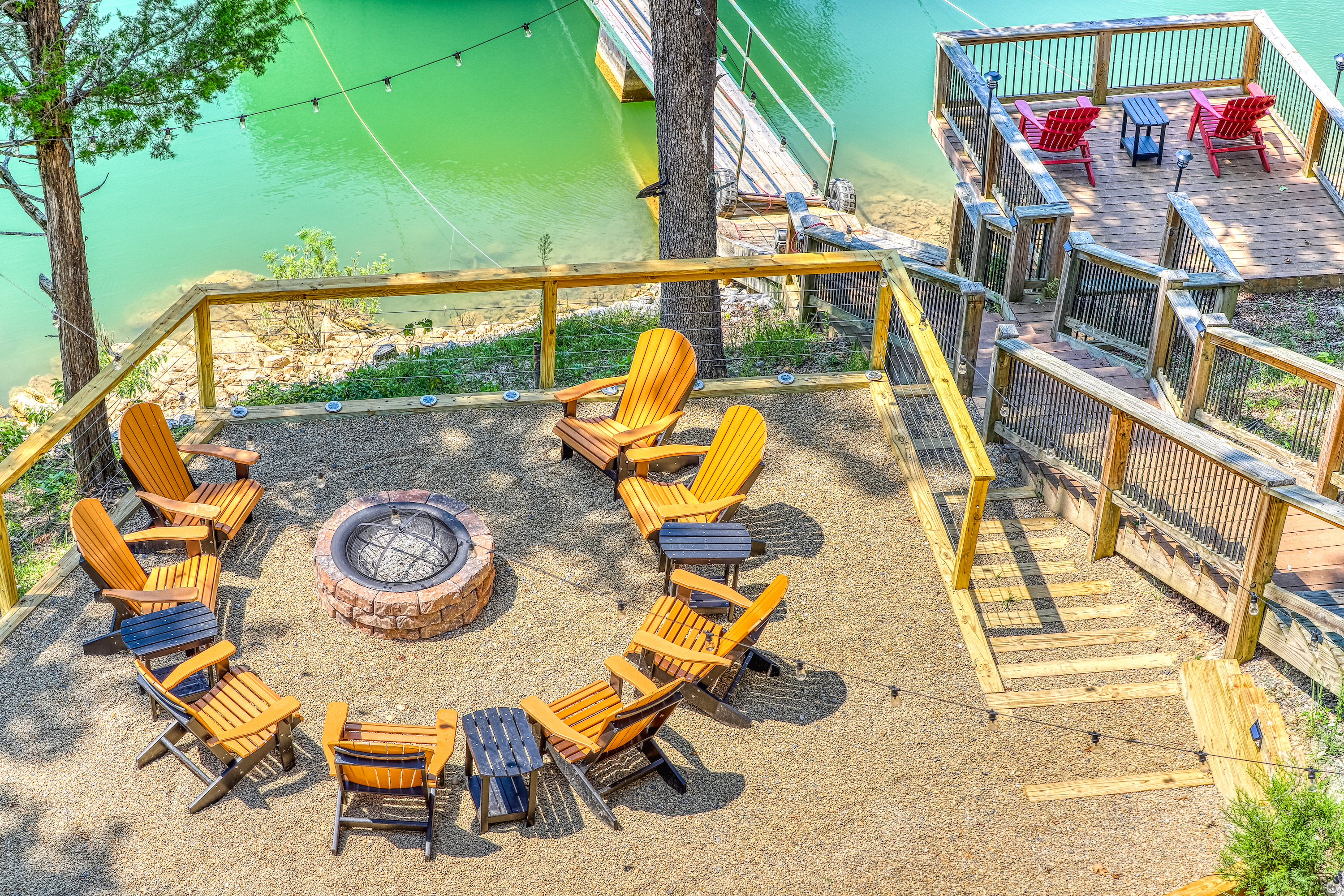 Adirondack chairs around an outdoor fire pit overlooking a lake with a dock in Marynardville, TN.