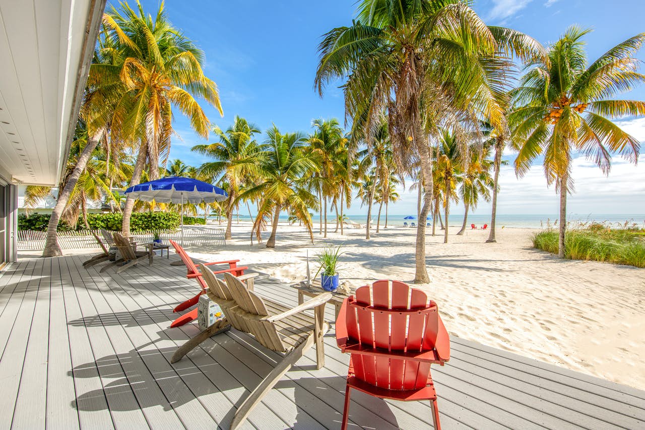 A wood deck to a beachfront vacation rental in Islamorada, FL with outdoor chairs.