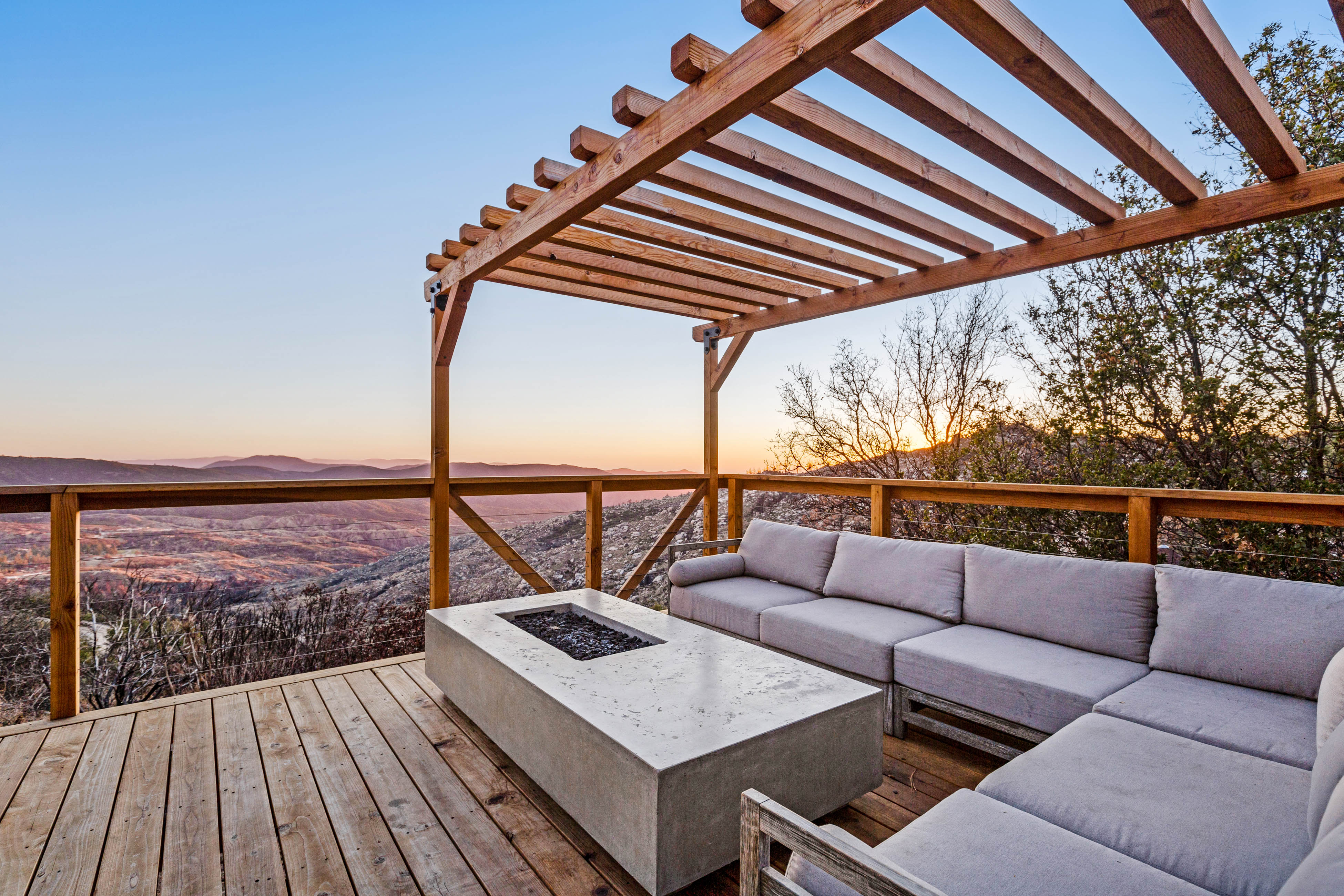 outdoor sectional surrounds a fire table on a deck overlooking mountains