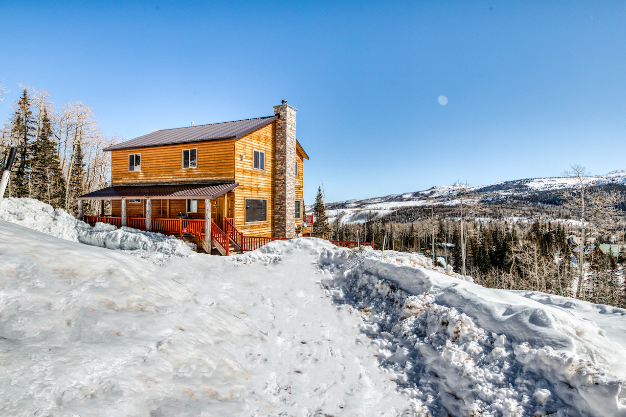 The exterior of a vacation rental cabin surrounded by snow in Brian Head, UT.