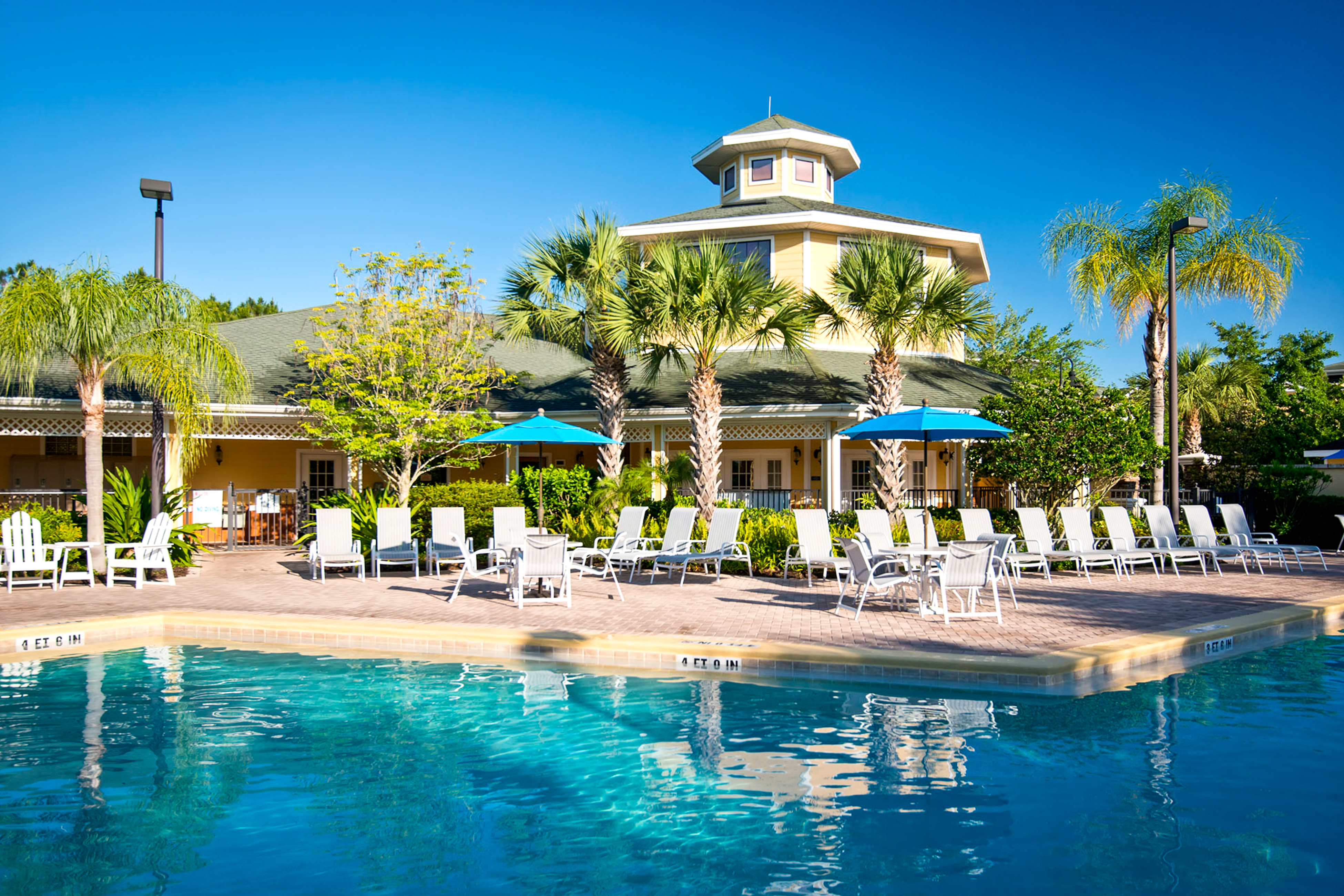 Caribe Cove Resort pool in Kissimmee, FL surrounded by lounge chairs and palm trees