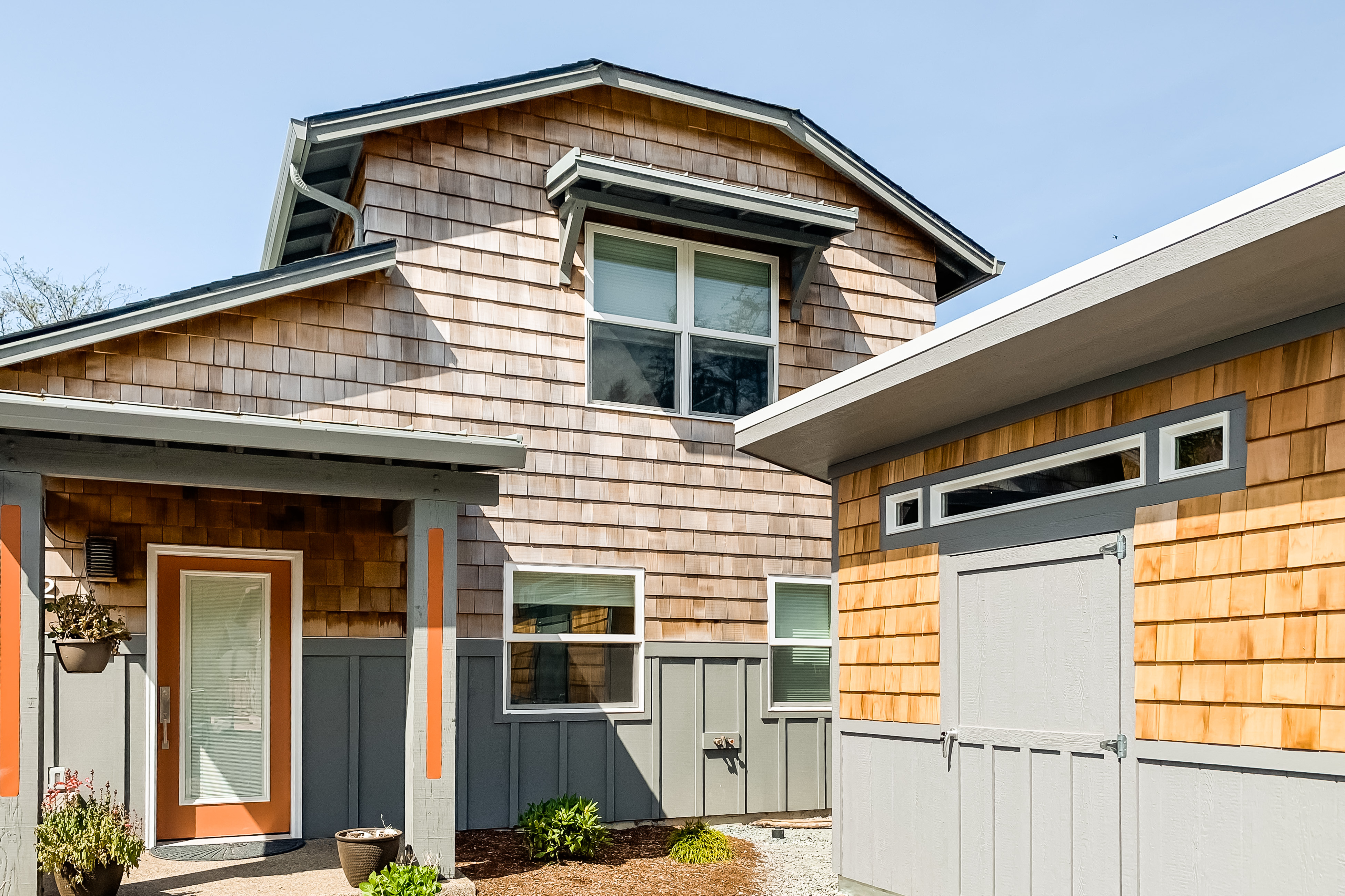 rockaway beach vacation home with wood siding and an orange front door