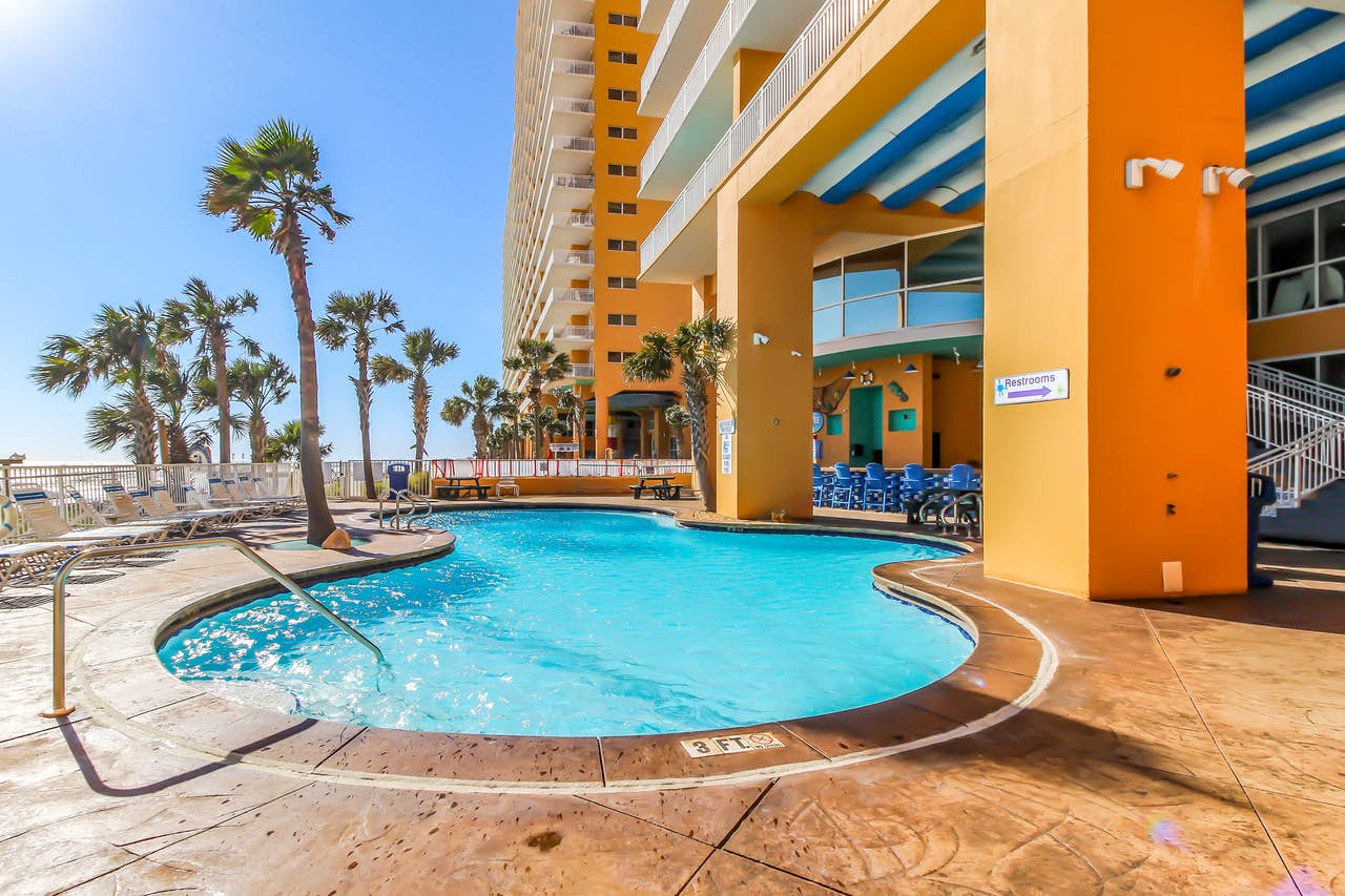 An outdoor pool at a large resort with palm trees in Panama City Beach, FL.