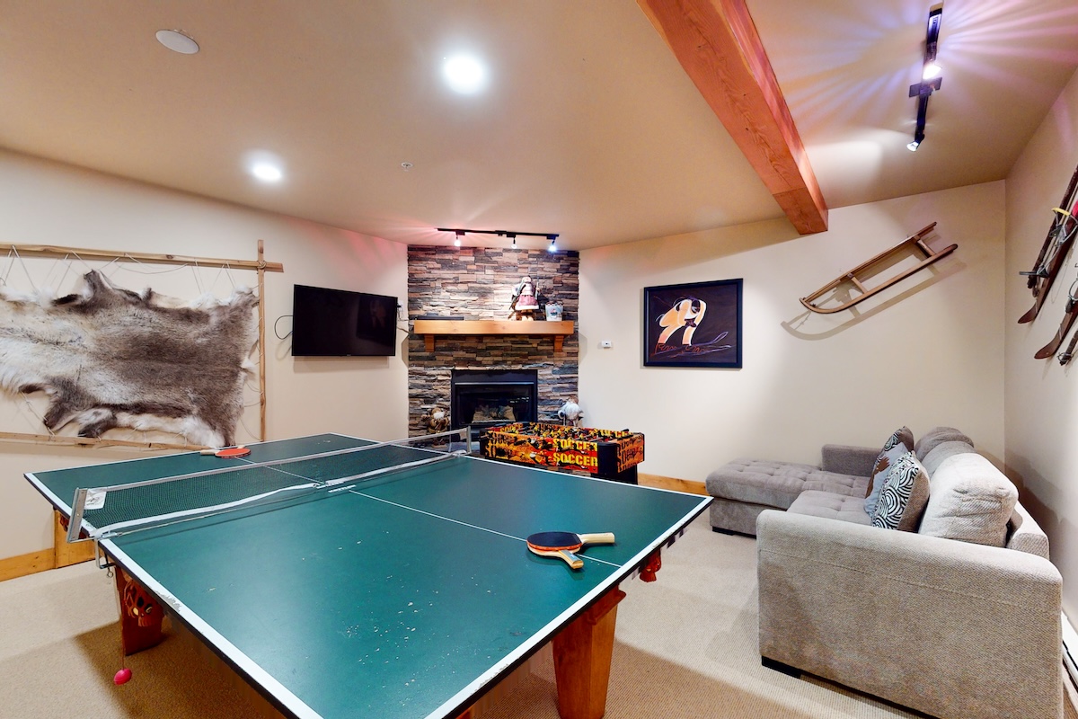 A ping pong table in a room with a fireplace and ski decor.