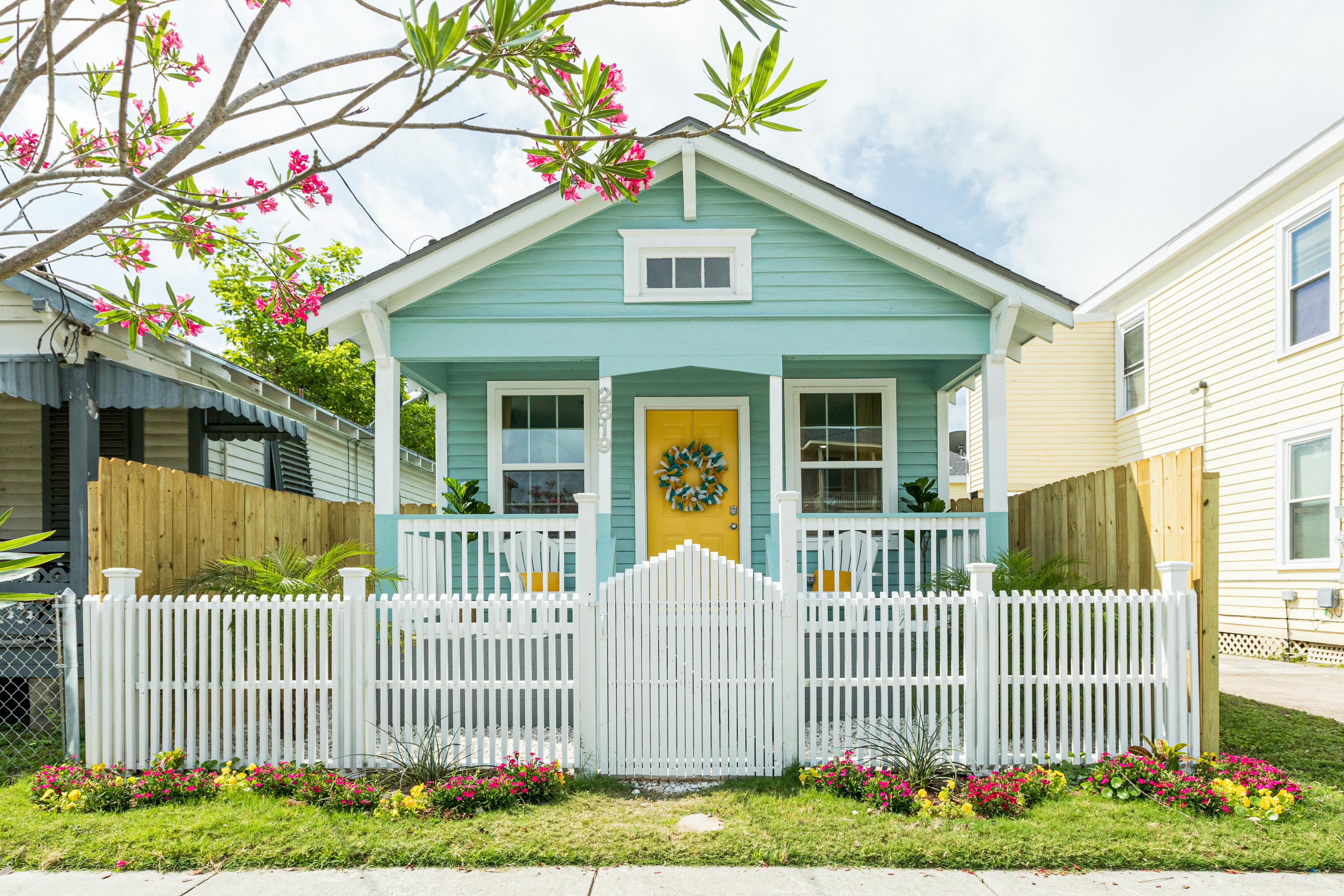 Quaint turquoise vacation home with a front deck and white picket fence in Galveston, TX