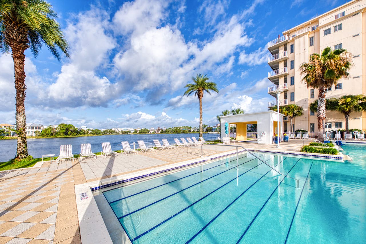 An outdoor pool to a condominium complex in Panama City Beach, FL near the beach with palm trees.