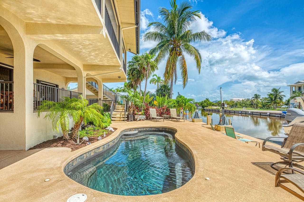 Small outdoor pool at a resort in Florida Keys near a canal and palm trees.