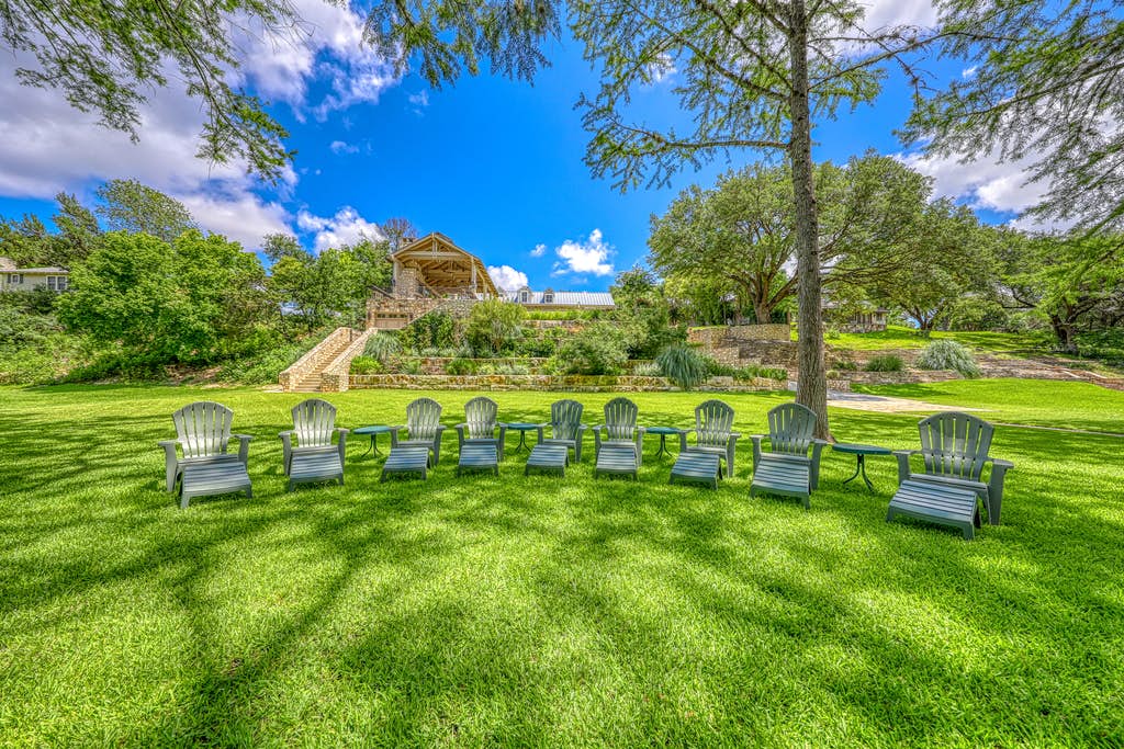 9 lawn chairs set up in large well-manicured lawn of vacation home