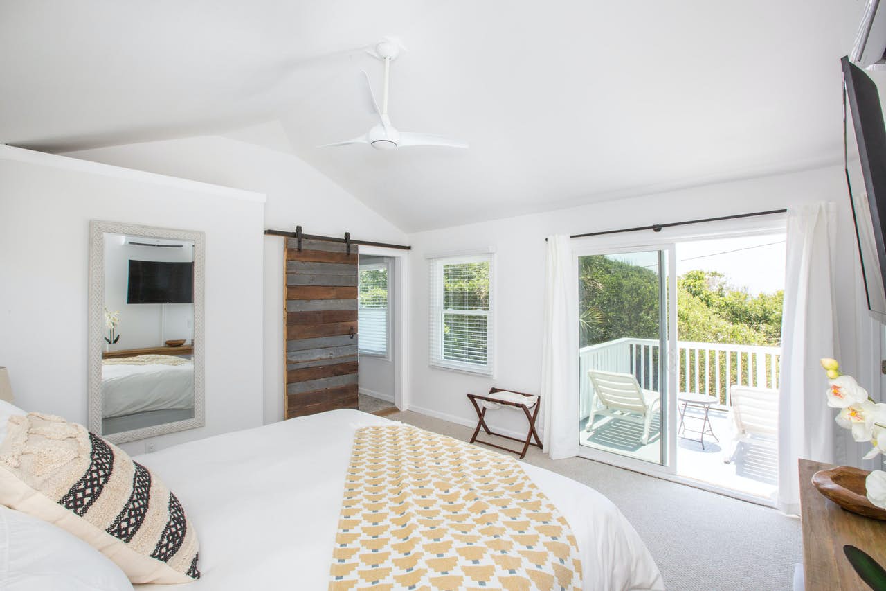 clean, white interior of folly beach vacation rental bedroom with balcony