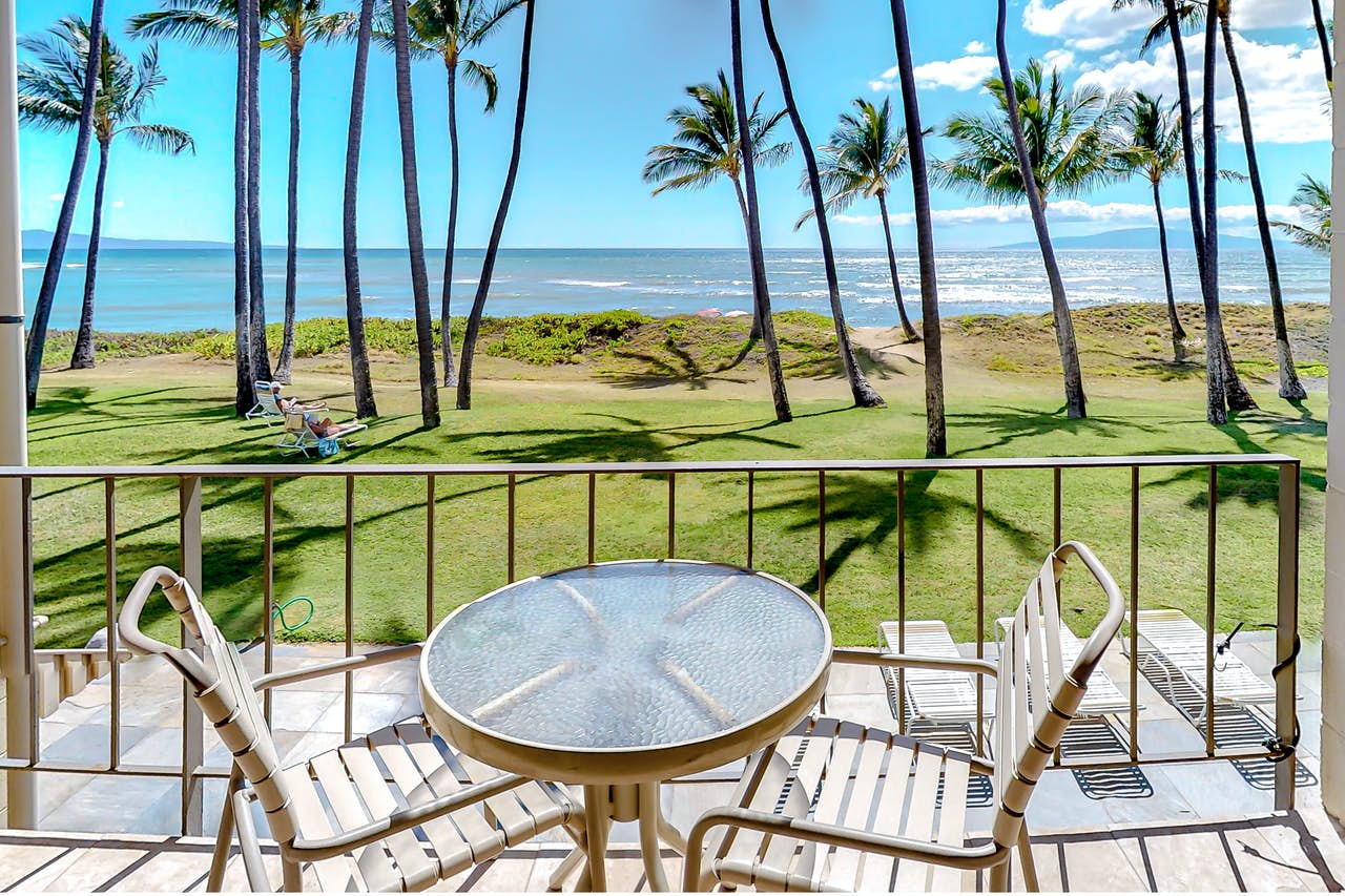 Outdoor patio with an oceanfront view and palm trees on a sunny day.