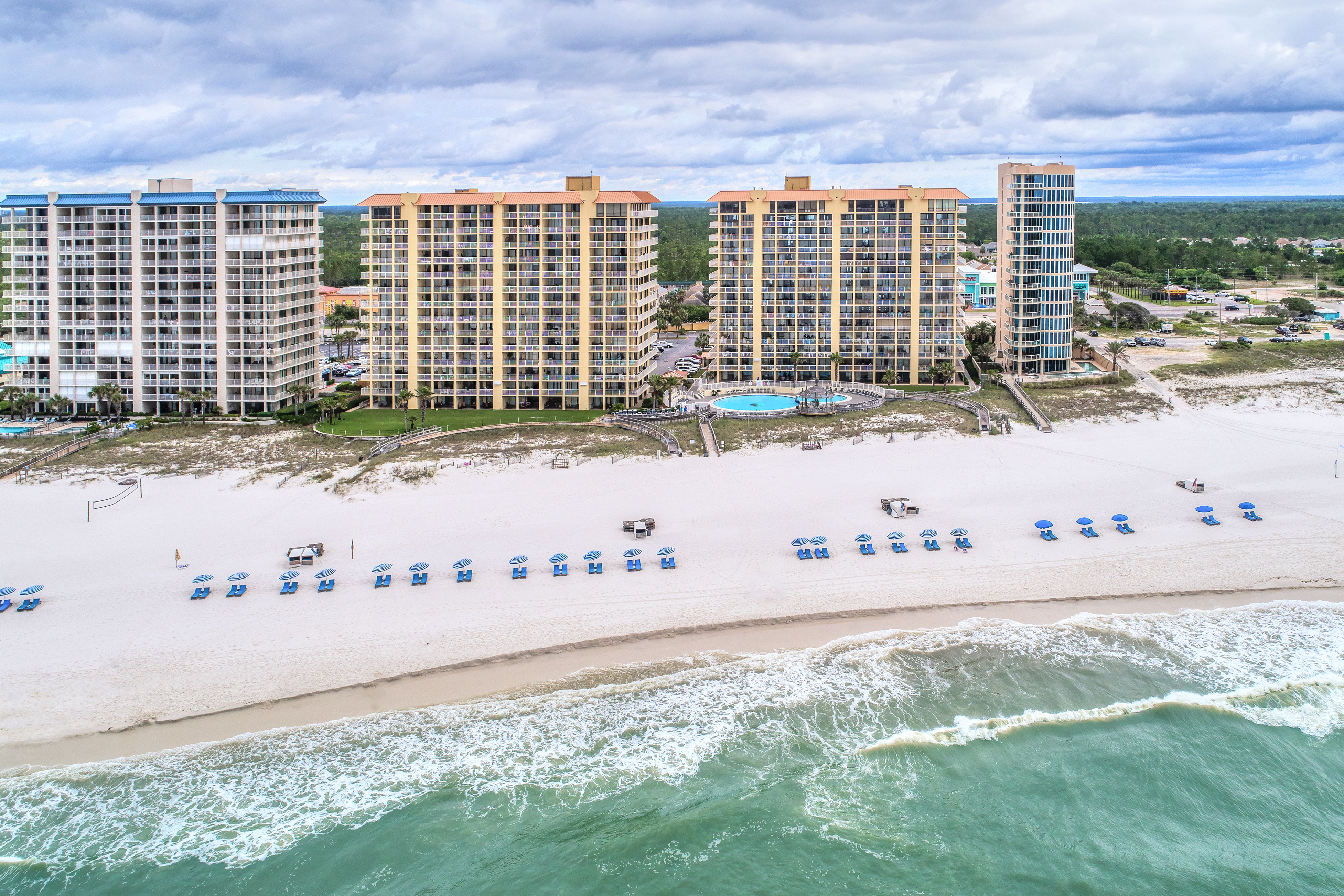Drone shot of hotels and the coastline lined with chairs in Miramar Beach.