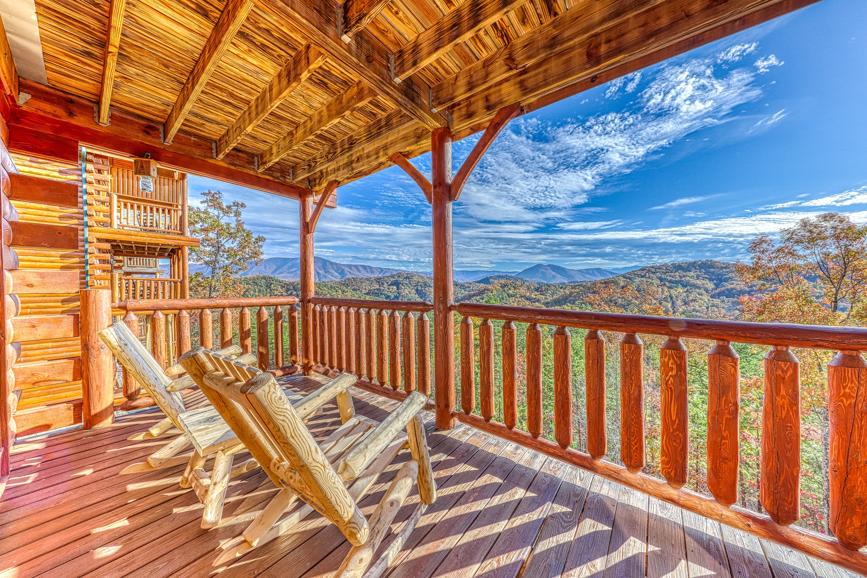 The balcony of a cabin rental with adirondack chairs with a Smoky Mountain view in Pigeon Forge, TN.