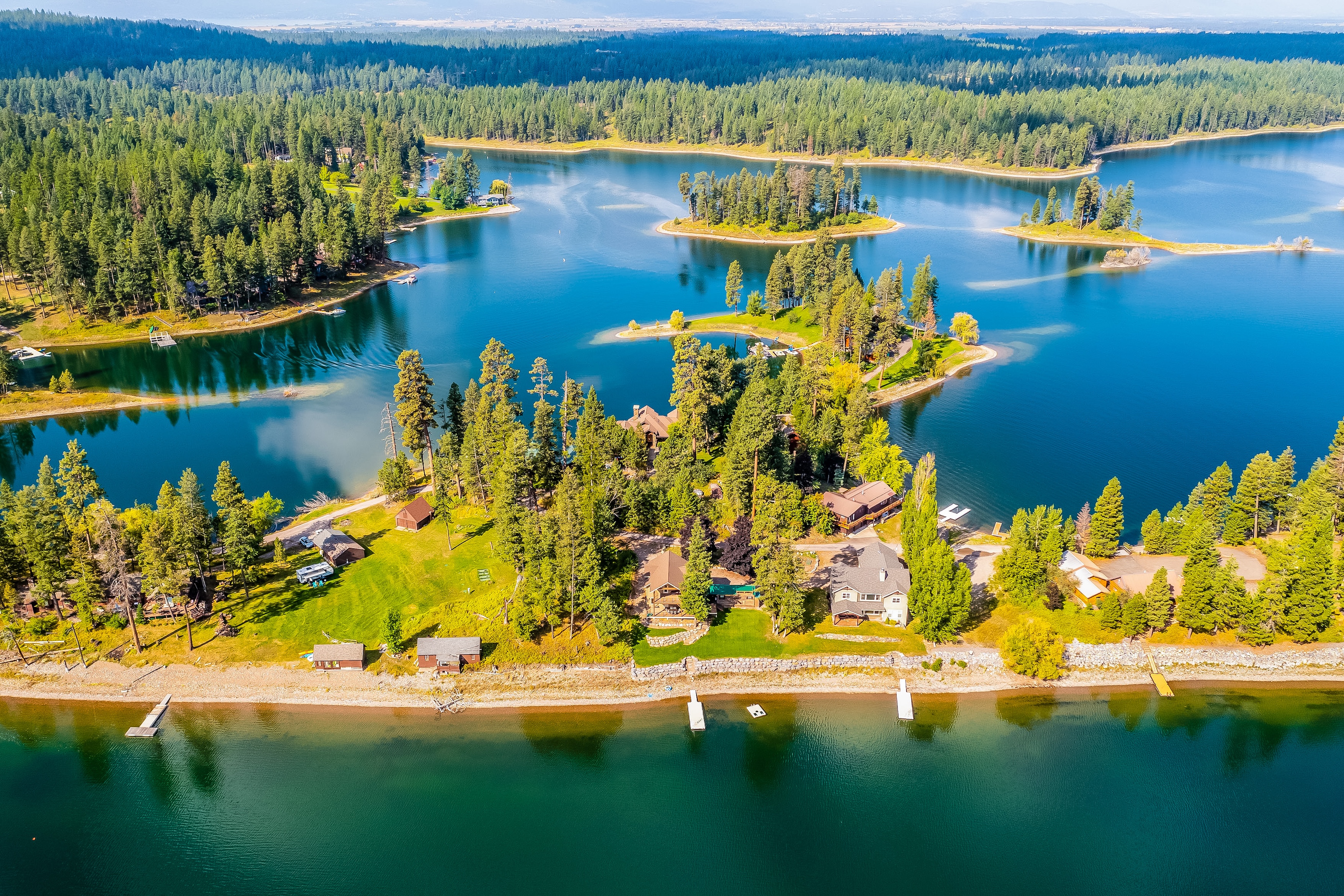 Aerial view of flathead lake in montana on a clear blue day with waterfront homes surrounding the lake