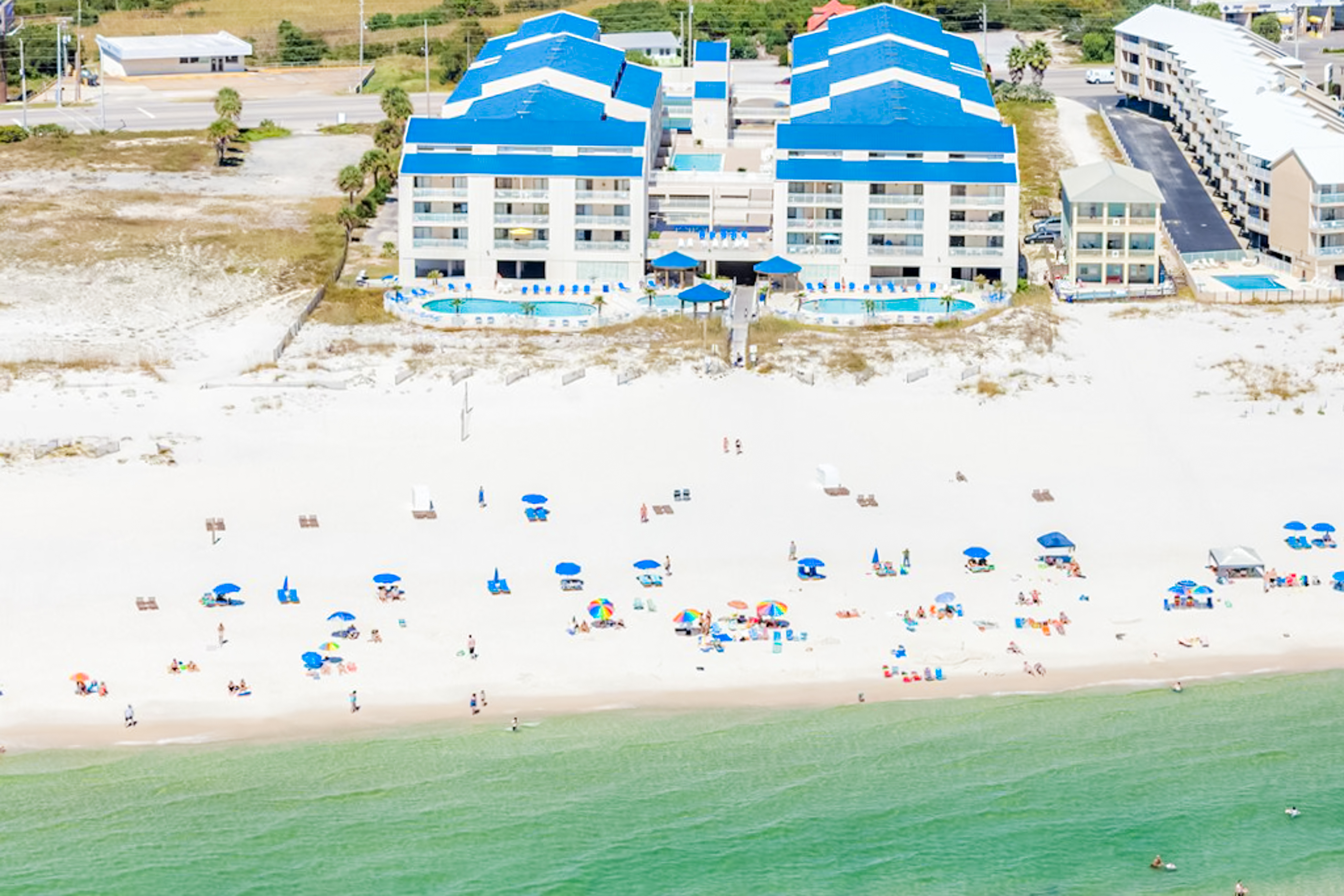 Aerial shot of the Sugar Beach Condos in Orange Beach, AL from the beach with guests on the shore.