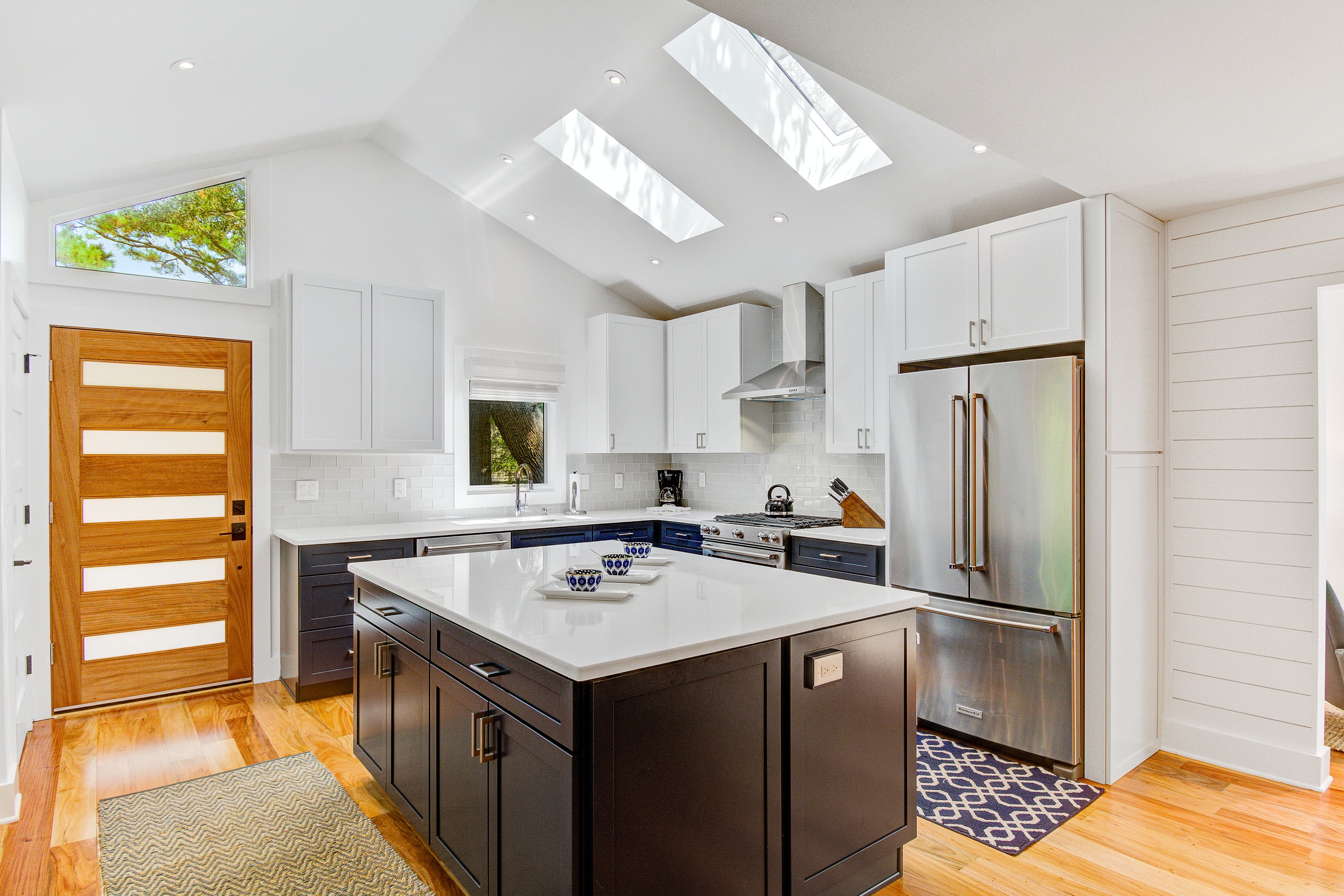 contemporary kitchen with stainless steel appliances, ample storage, skylights, and a custom island