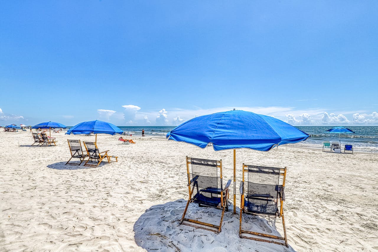 Spaced out beach chairs and sun umbrellas lined along the shore in Hilton Head, SC.
