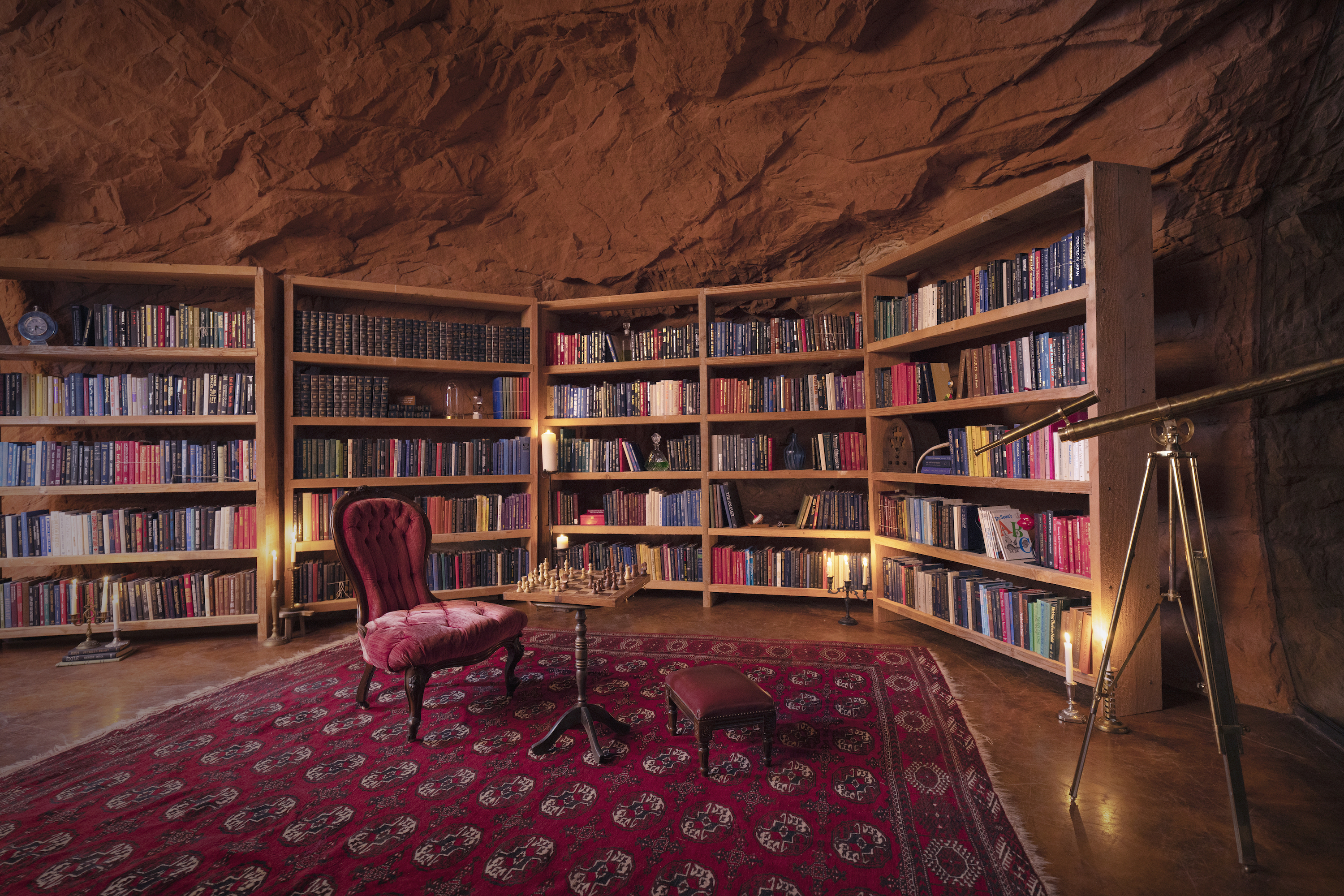 library full of books and a chess table with a single velvet tufted chair inside the grinch's cave