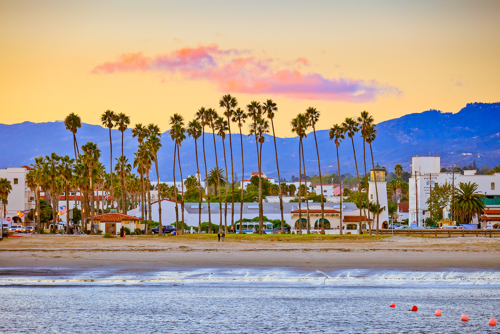 Santa Barbara beach lined with homes and palm trees at dusk.