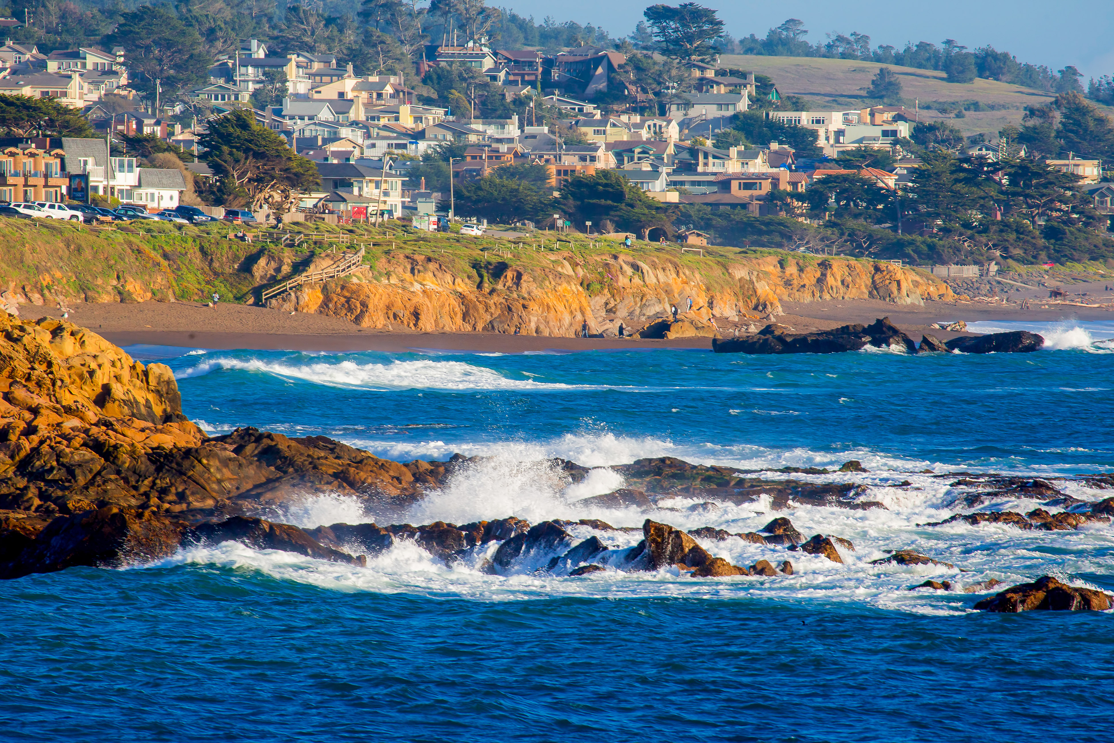 rocky and sandy coastline with the town of cambria, ca in the background