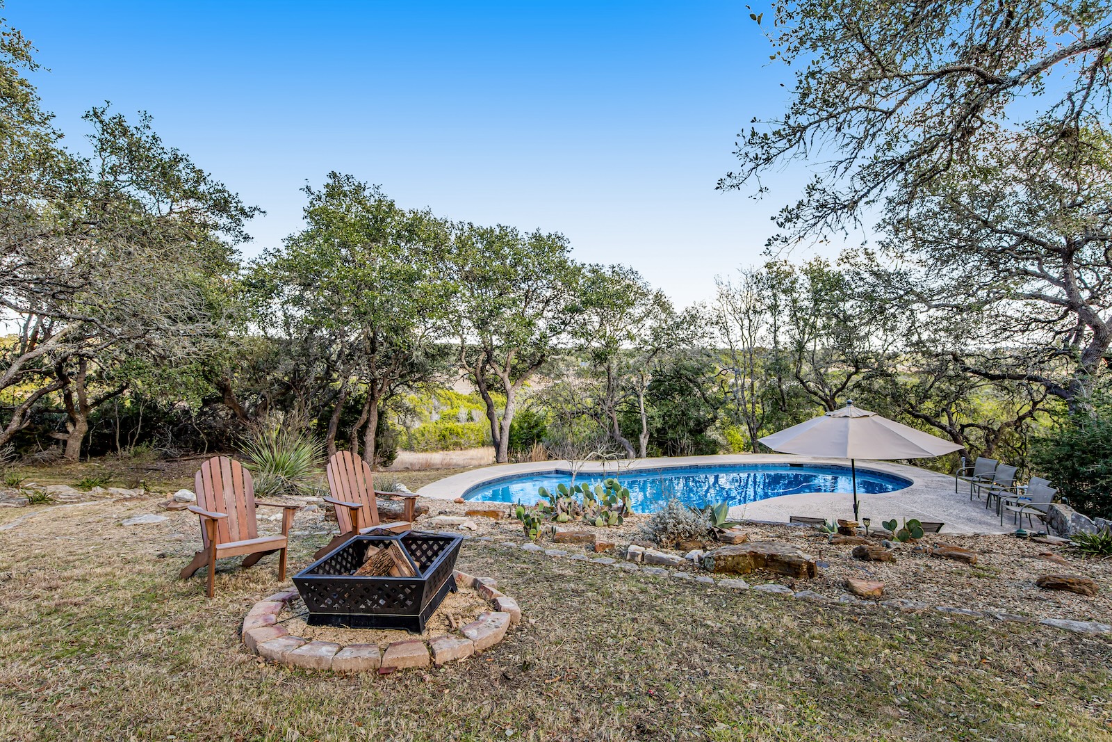 The backyard pool area of a vacation home with a fire pit in Dripping Springs, TX.