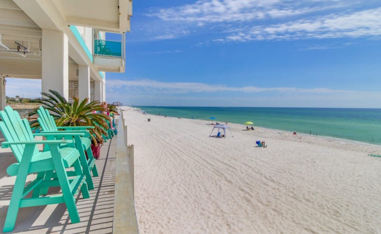 Outdoor beach chairs at a Panama City Beach, FL resort facing a sandy beach and ocean.