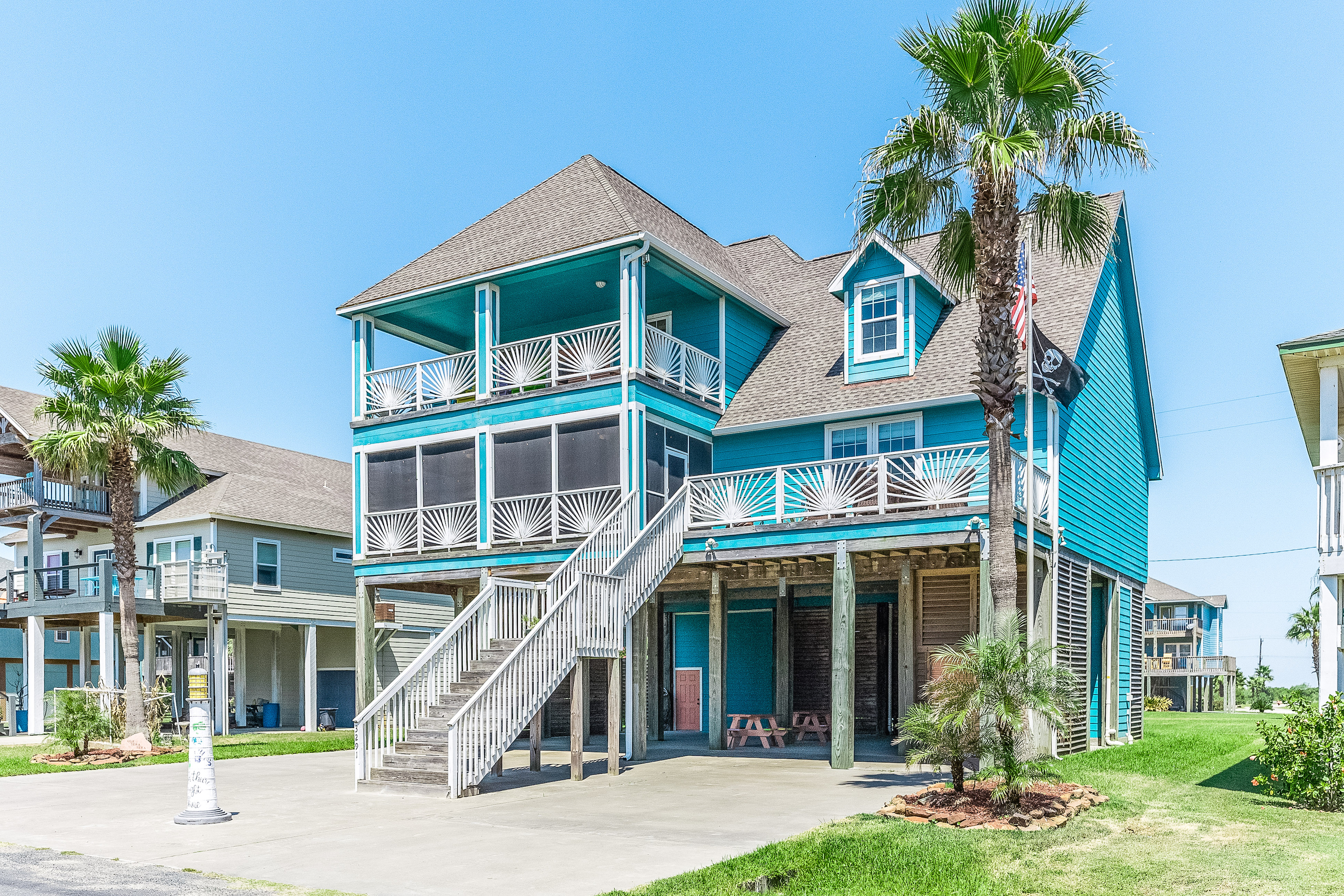 blue beach house in crystal beach, texas surrounded by palm trees