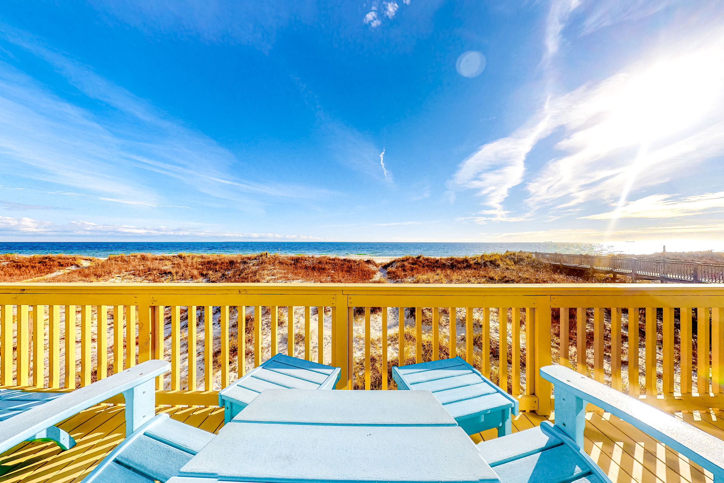 Blue deck furniture sits on yellow deck of vacation rental in Gulf Shores, AL