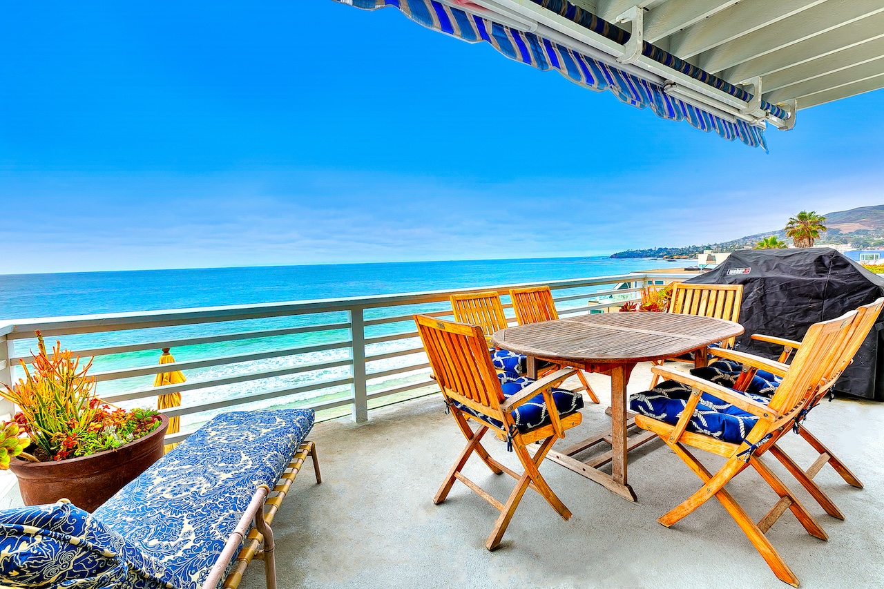 The deck overlooking the ocean with table and chairs, including other amenities like a BBQ, at a Laguna Beach, CA vacation rental