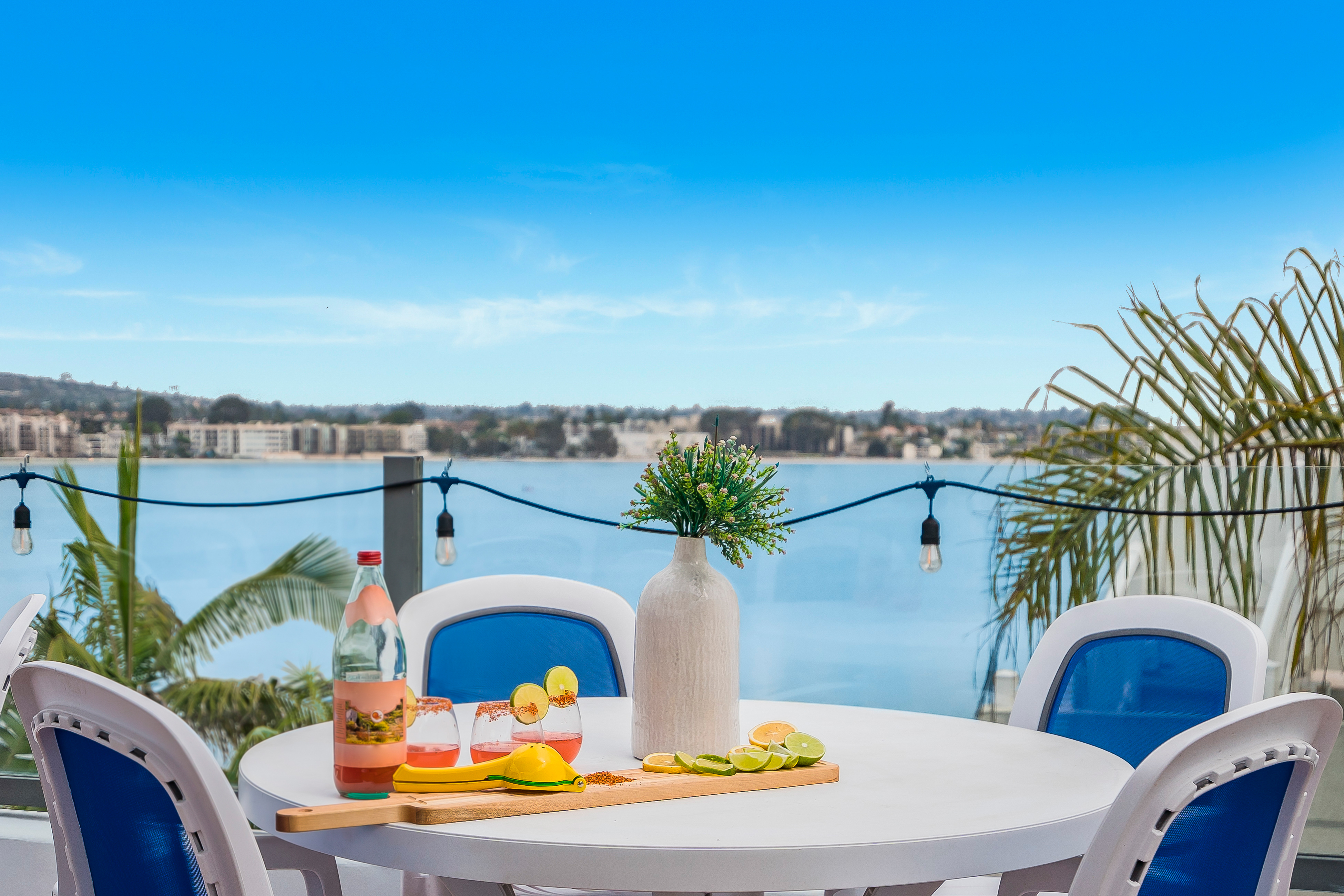 A bistor table with lines and oranges accompanied with drinks overlooking a bay in California.