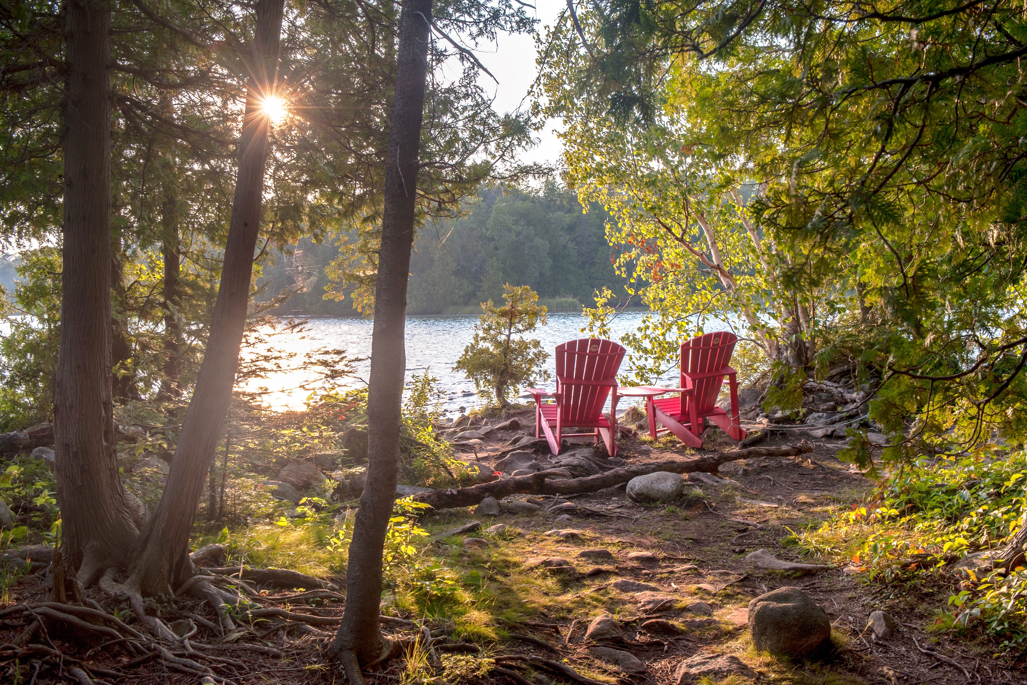 two red adirondack chairs face the georgian bay in ontario