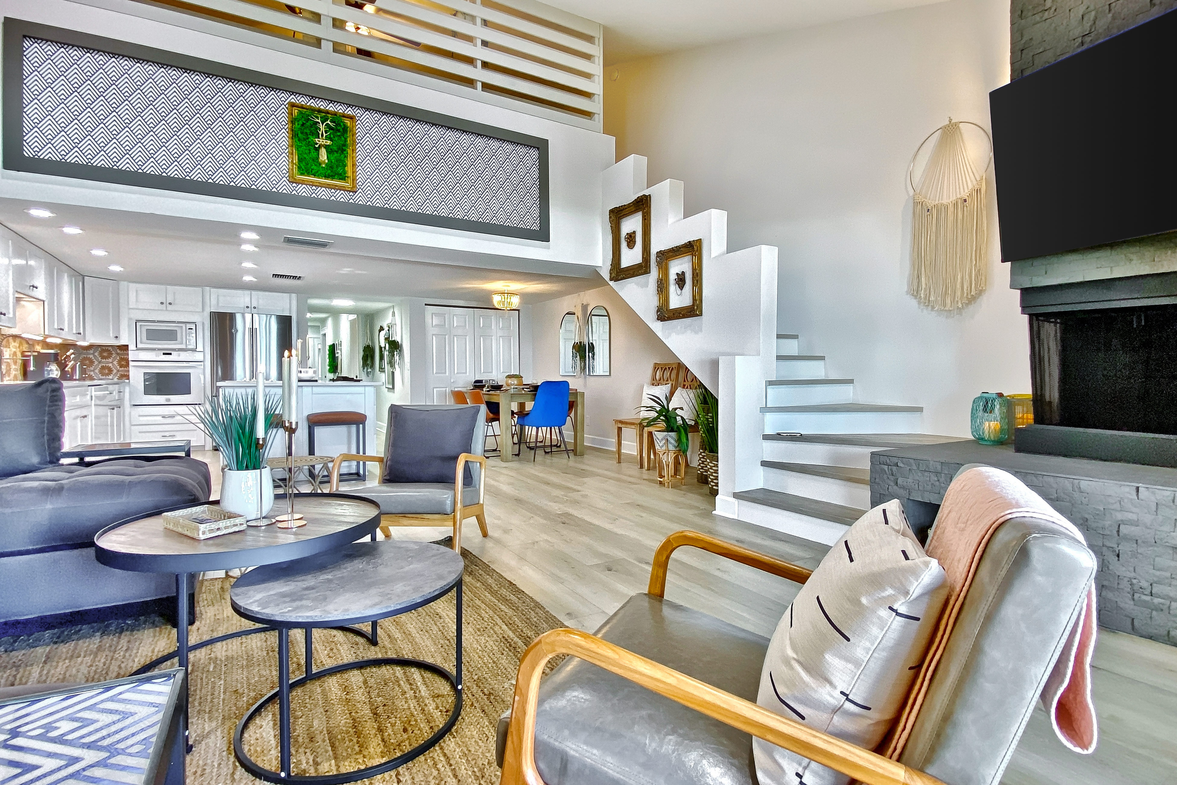 chic living space with chair, circular coffee tables, a fireplace, and a tv with white stairs leading upstairs