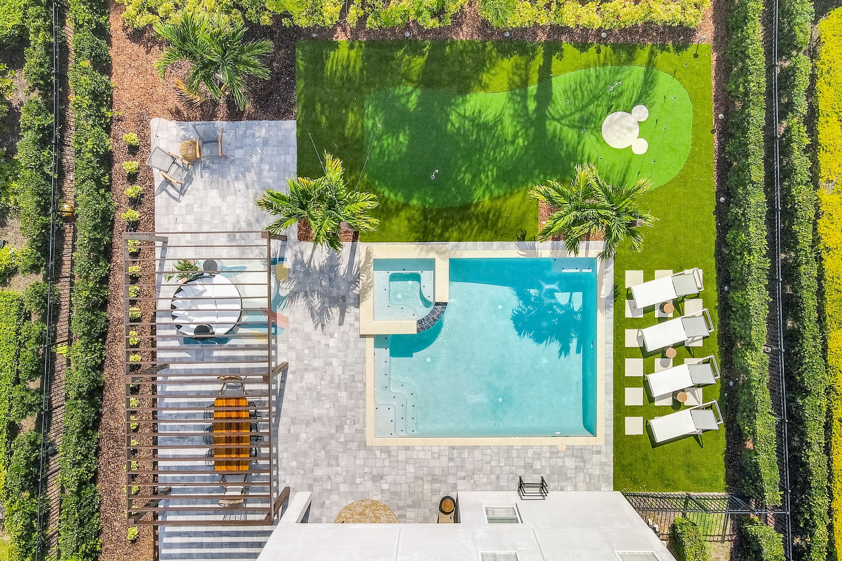 aerial view of florida home with outdoor pool, mickey-shaped putting green, outdoor dining table