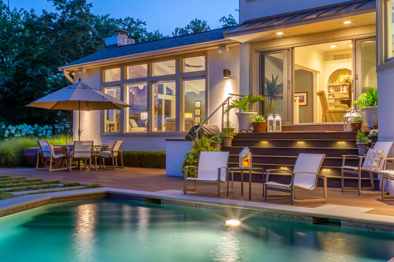 The back area of a vacation rental with a pool in Annapolis surrounded by chairs at dawn.
