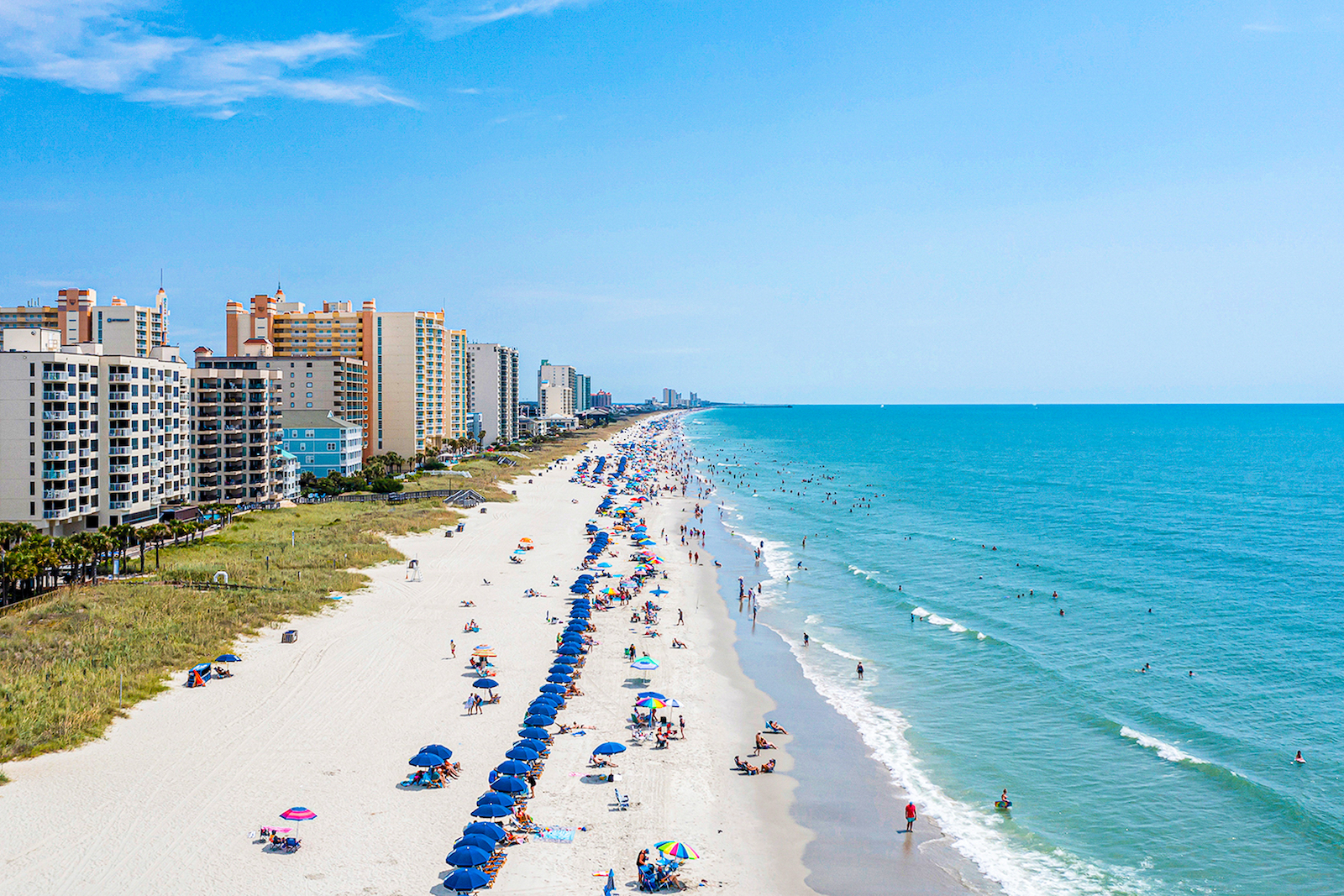 Myrtle Beach coastline with people enjoying themselves by swimming and sunbathing.
