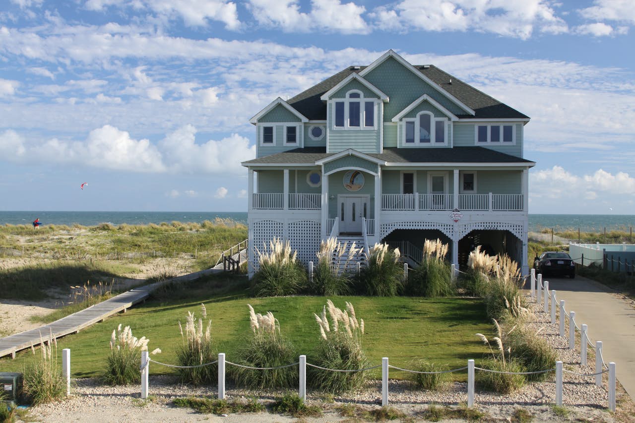 A large beach house rental with a boardwalk and driveway near the ocean in Outer Banks, NC.