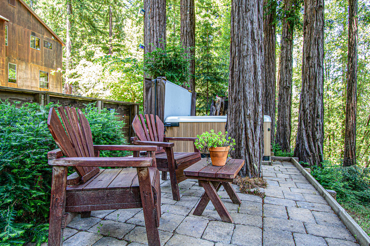 rustic outdoor wooden furniture on a stone pad next to a hot tub