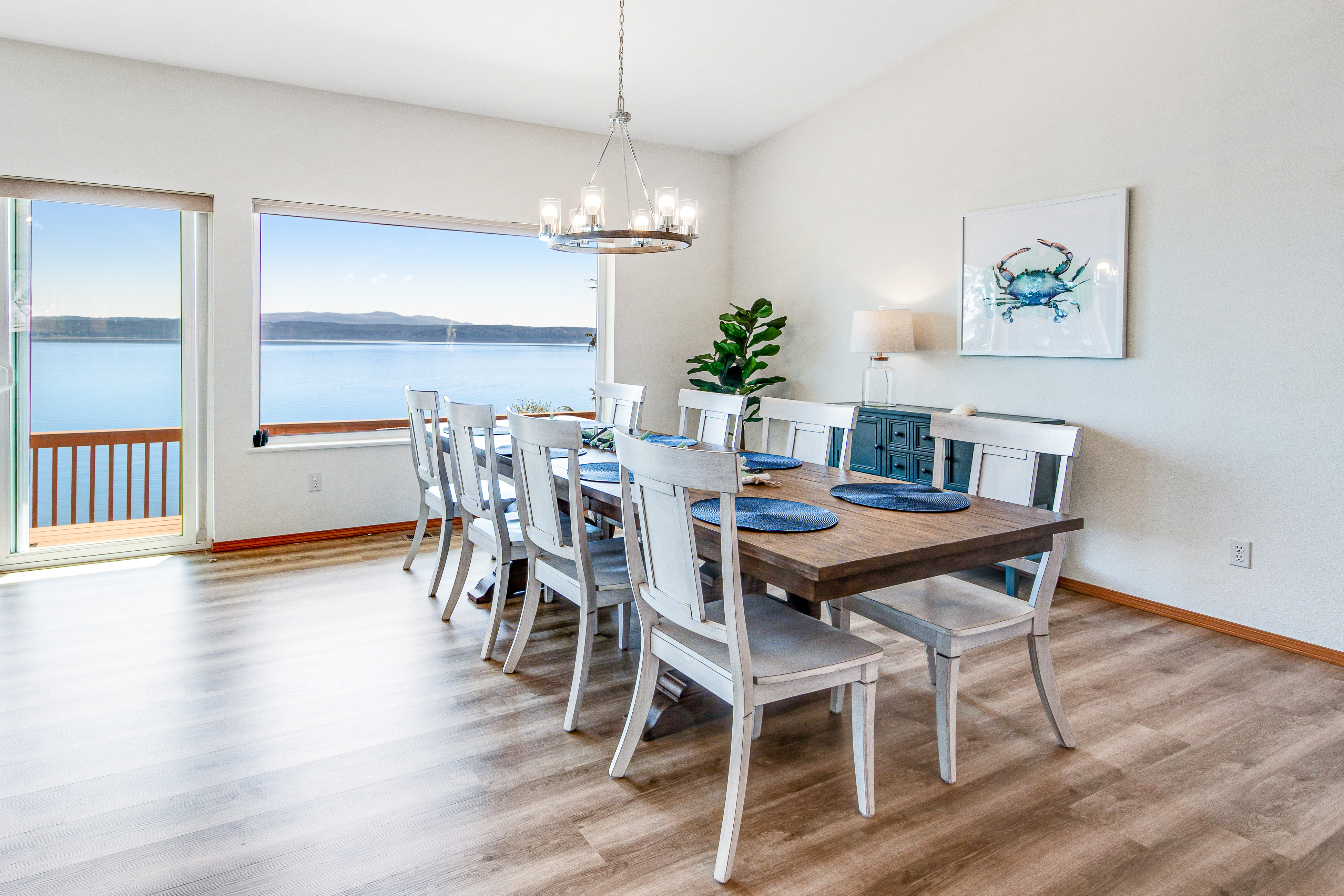 A dining room in a Brinnon, WA vacation rental with a wooden dining table and a view of a lake and mountain.