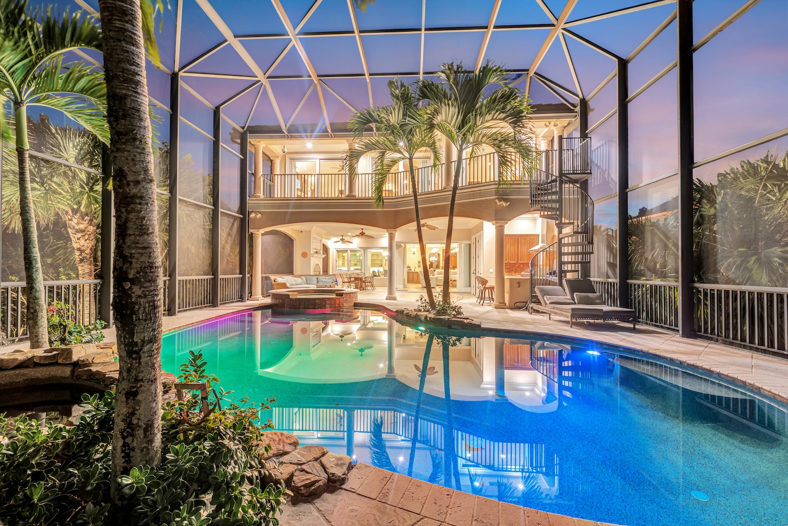 The pool area and the back of a vacation home in Florida lined with exotic plants.