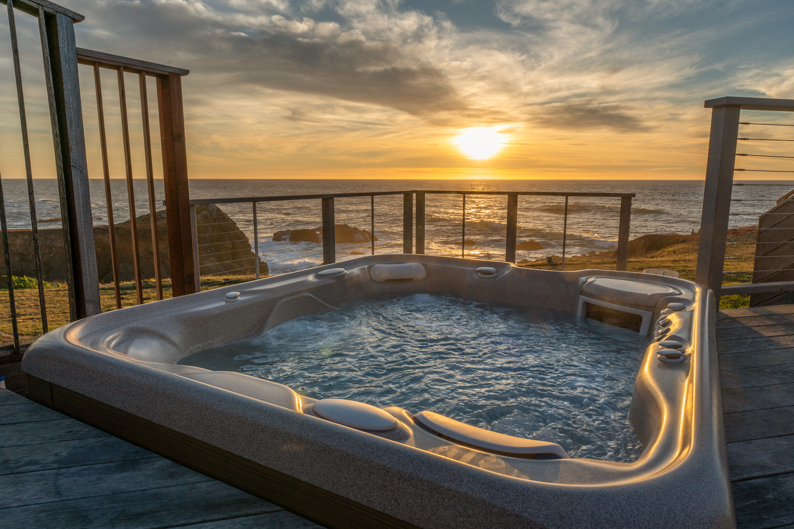 The hot tub overlooking a the ocean during sunset at a Fort Bragg vacation rental.